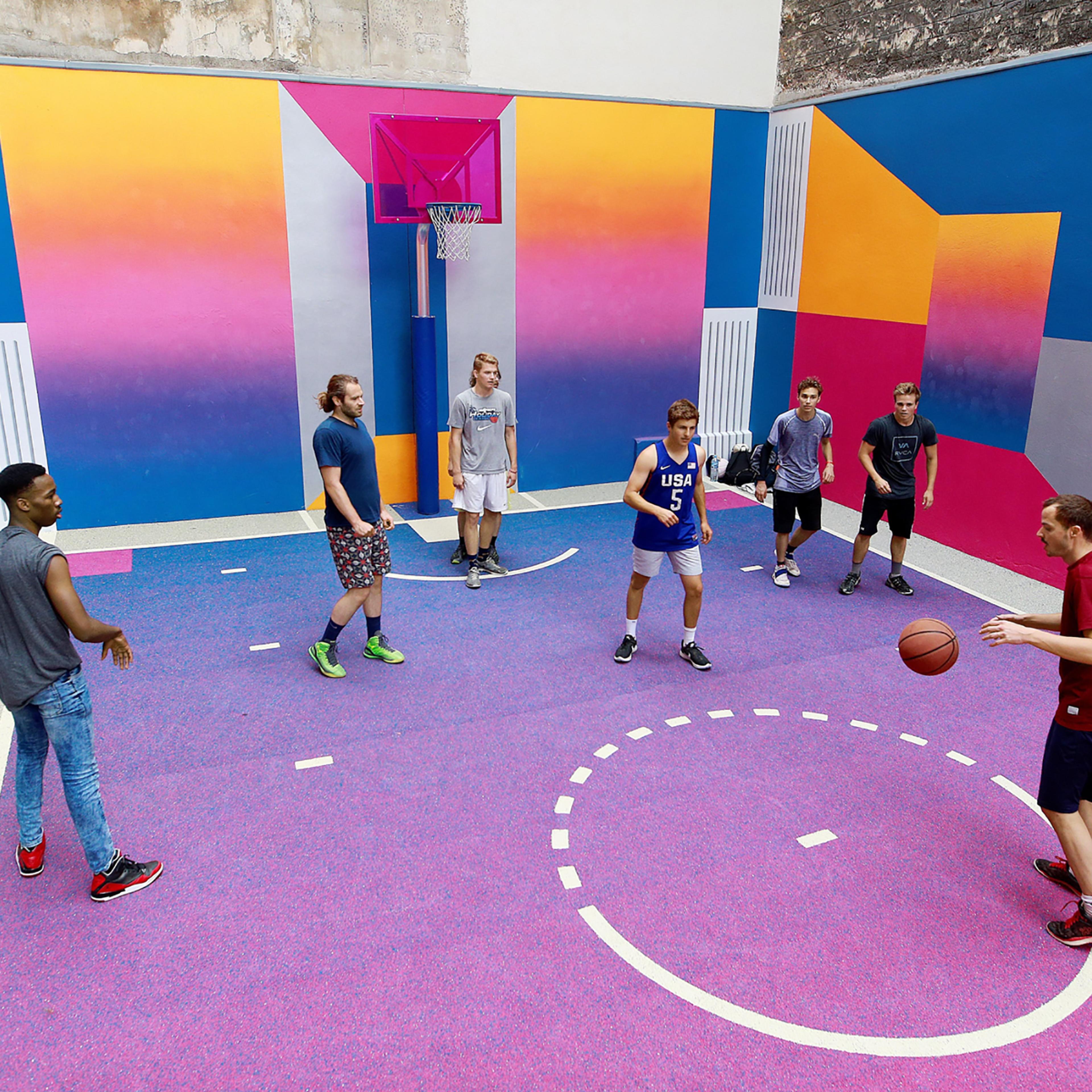 Youth play basketball at the Duperre Pigalle playground in Paris, on June 29, 2017