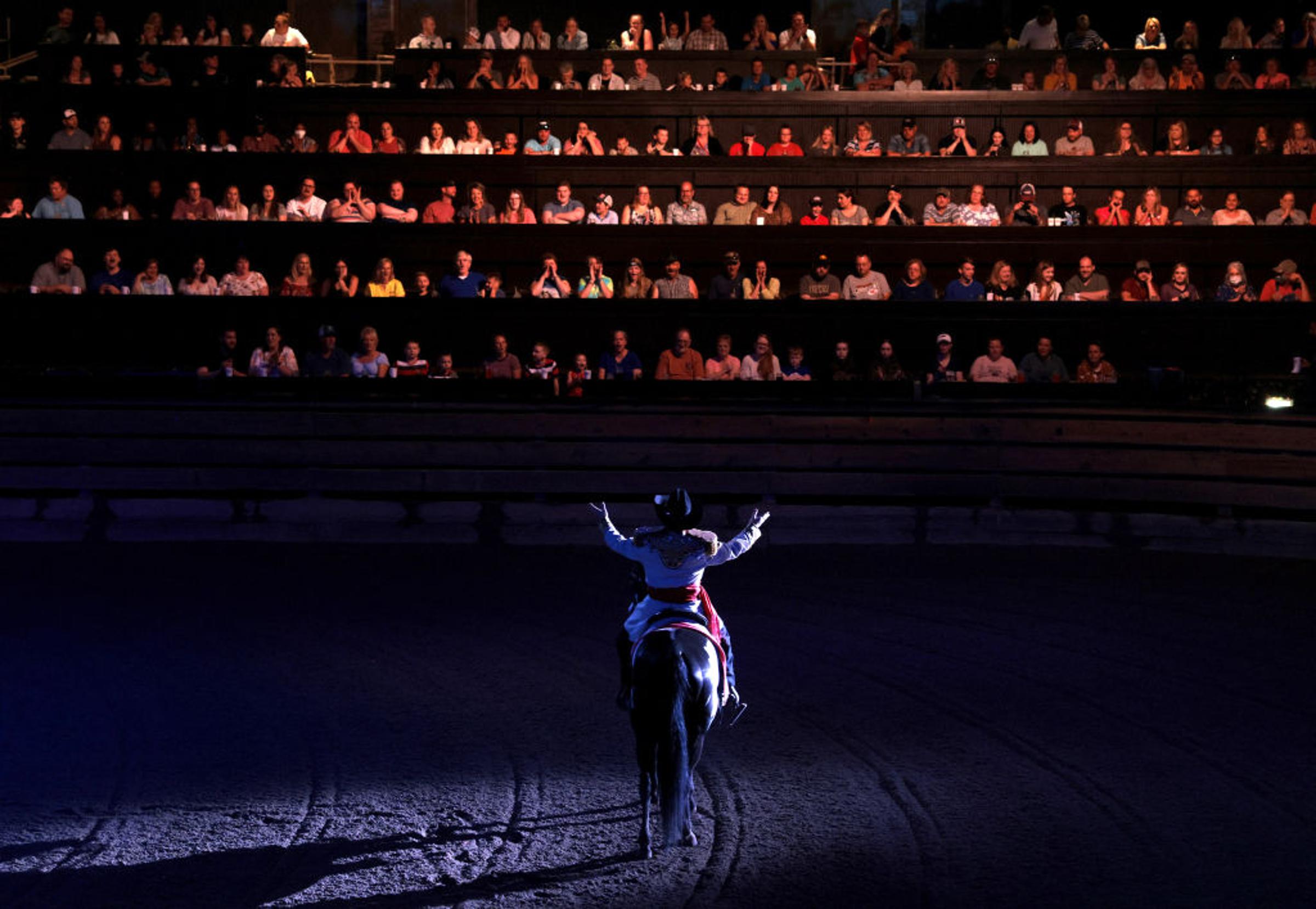 A performer spreads his arms out to those seated in The South as he divides the room of diners at Dolly Parton's Stampede into factions of North and South which will cheer on their teams as they compete in various events like barrel riding, chicken chasi