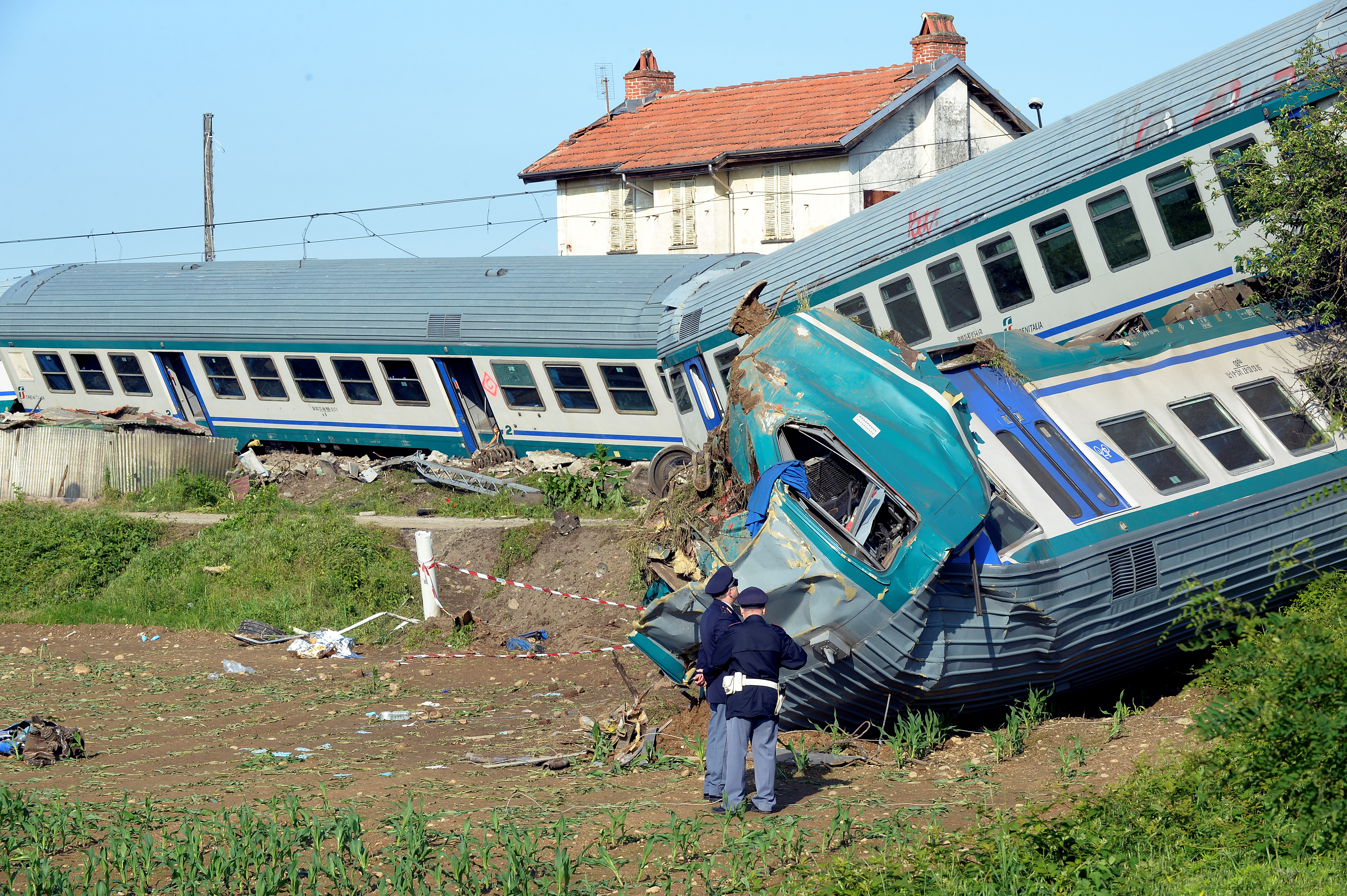 Italian police officers stand next to the twisted wreckage of a train that plowed into a truck last night in Caluso