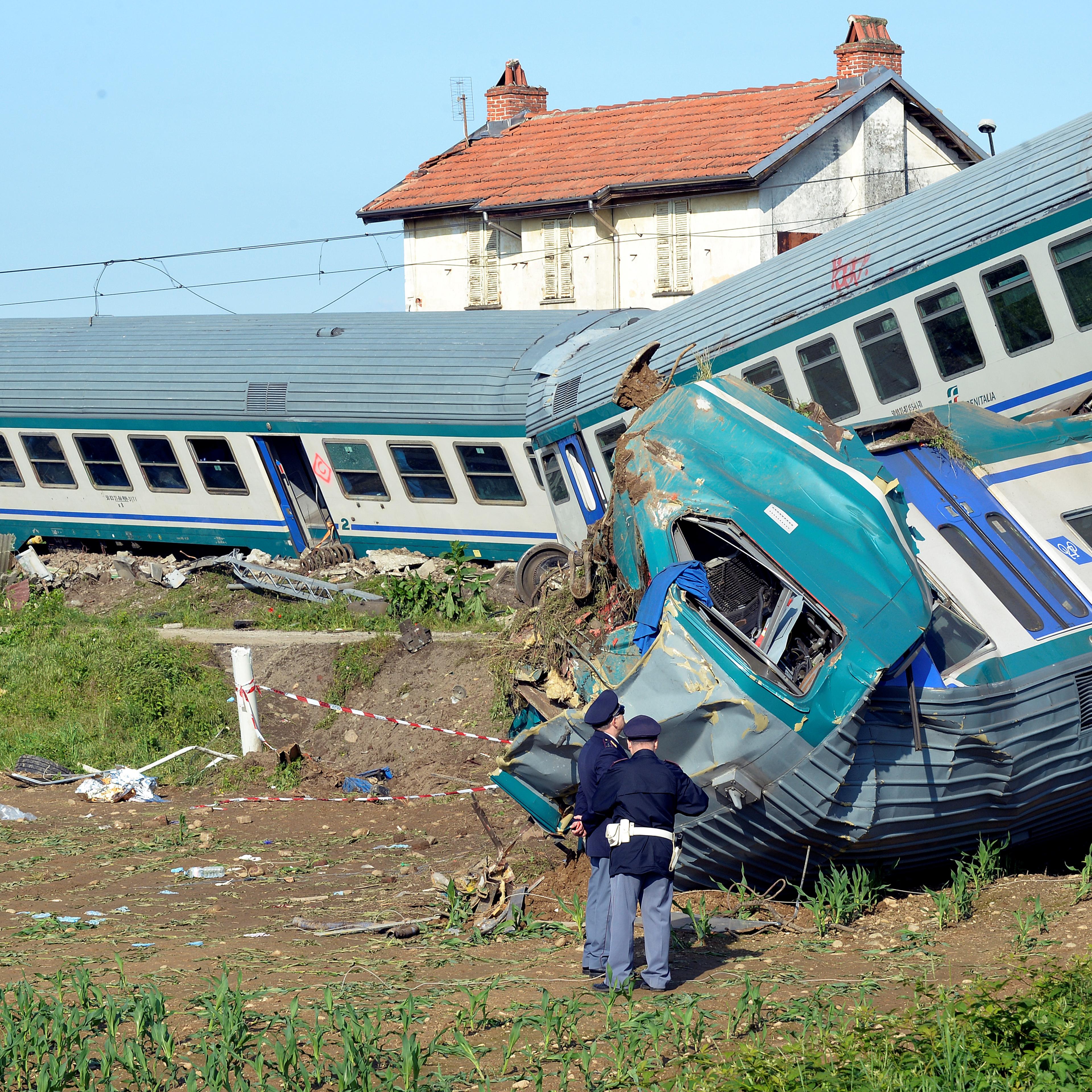 Italian police officers stand next to the twisted wreckage of a train that plowed into a truck last night in Caluso