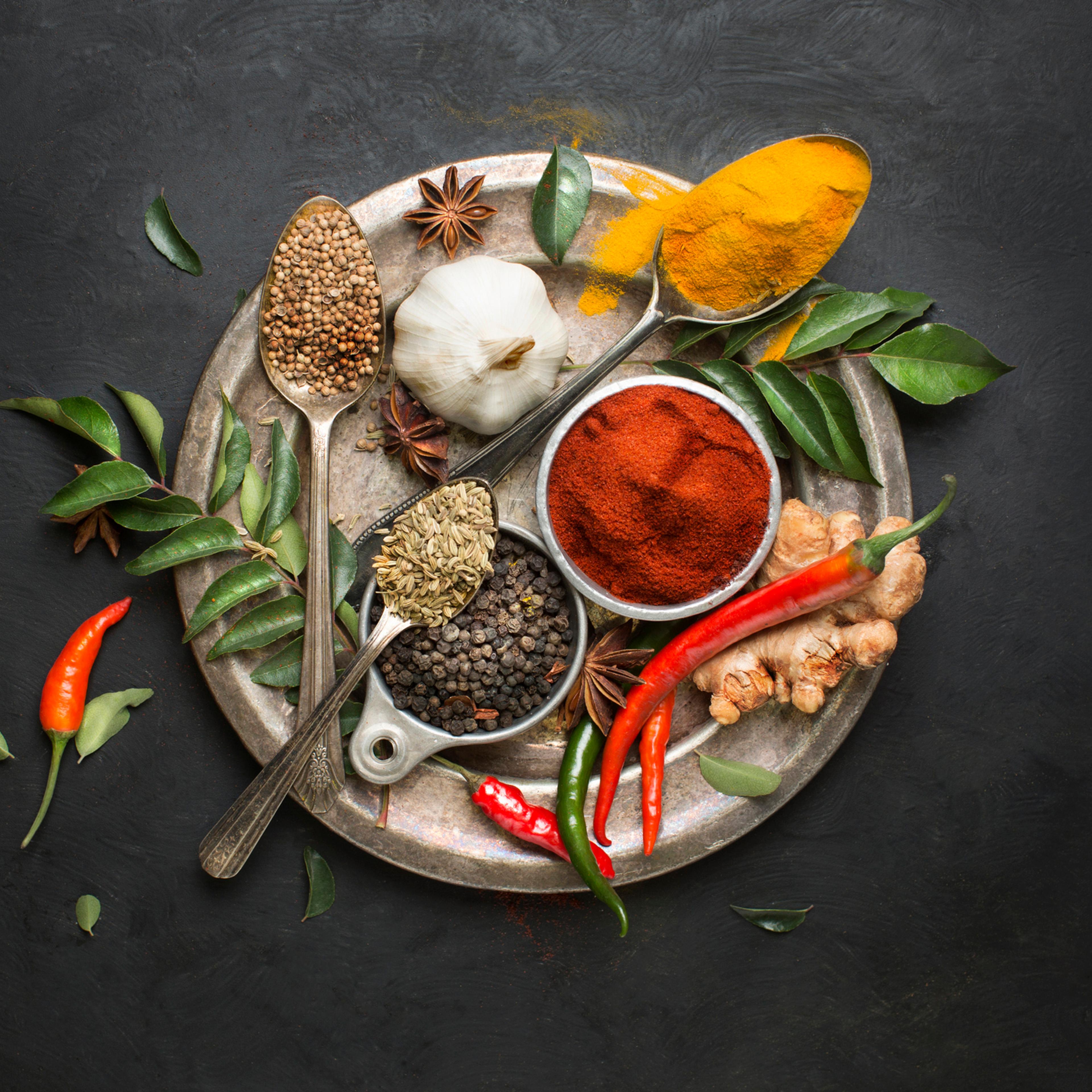 Flat lay overhead view herb and spices on textured black background.