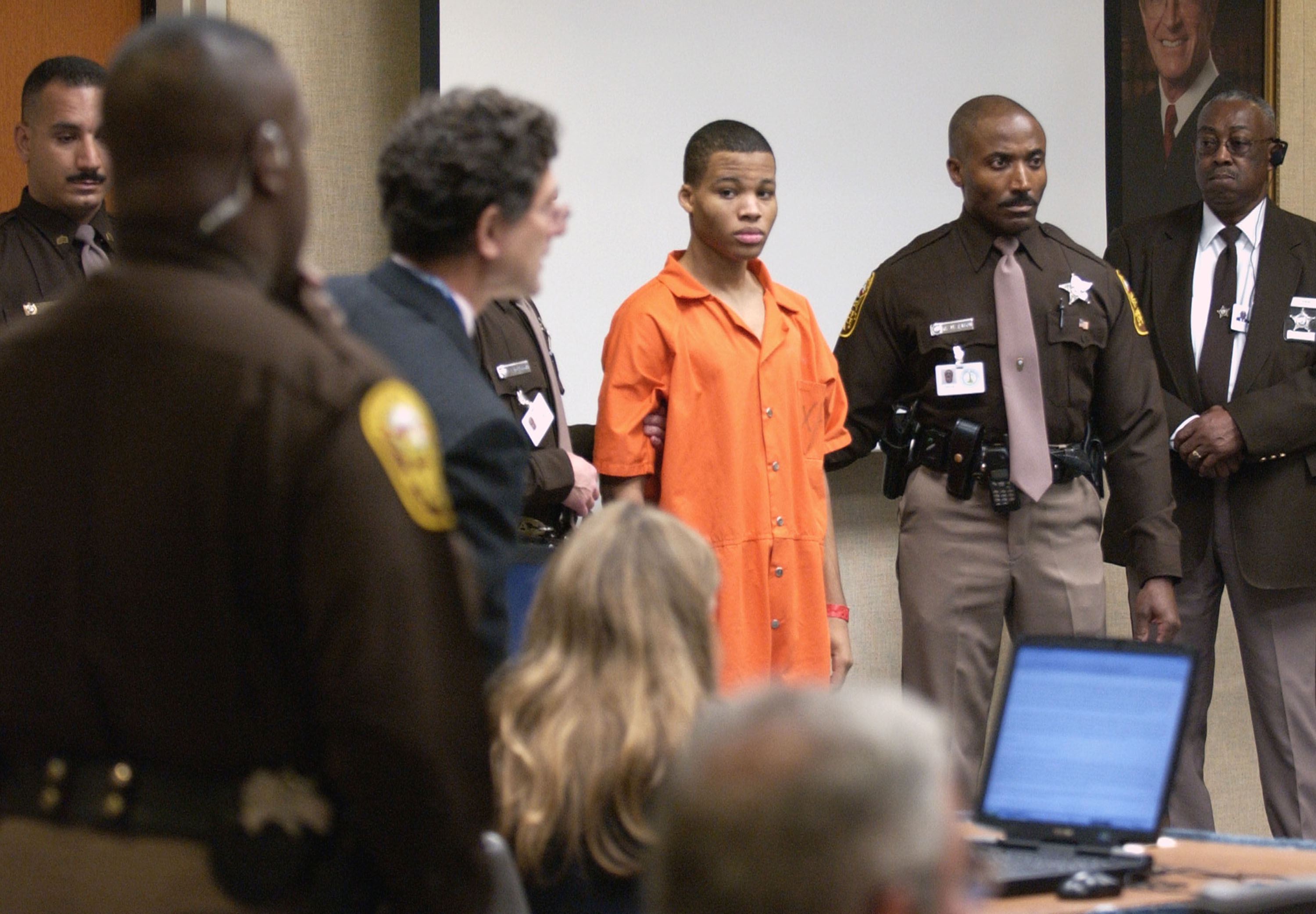 Sniper suspect Lee Boyd Malvo (C) is escorted by deputies as he is brought into court to be identified by a witness during the murder trial in courtroom 10 at the Virginia Beach Circuit Court October 22, 2003 in Virginia Beach, Virginia. Muhammad has decided not to represent himself in court and to turn his defense back to his attorneys.