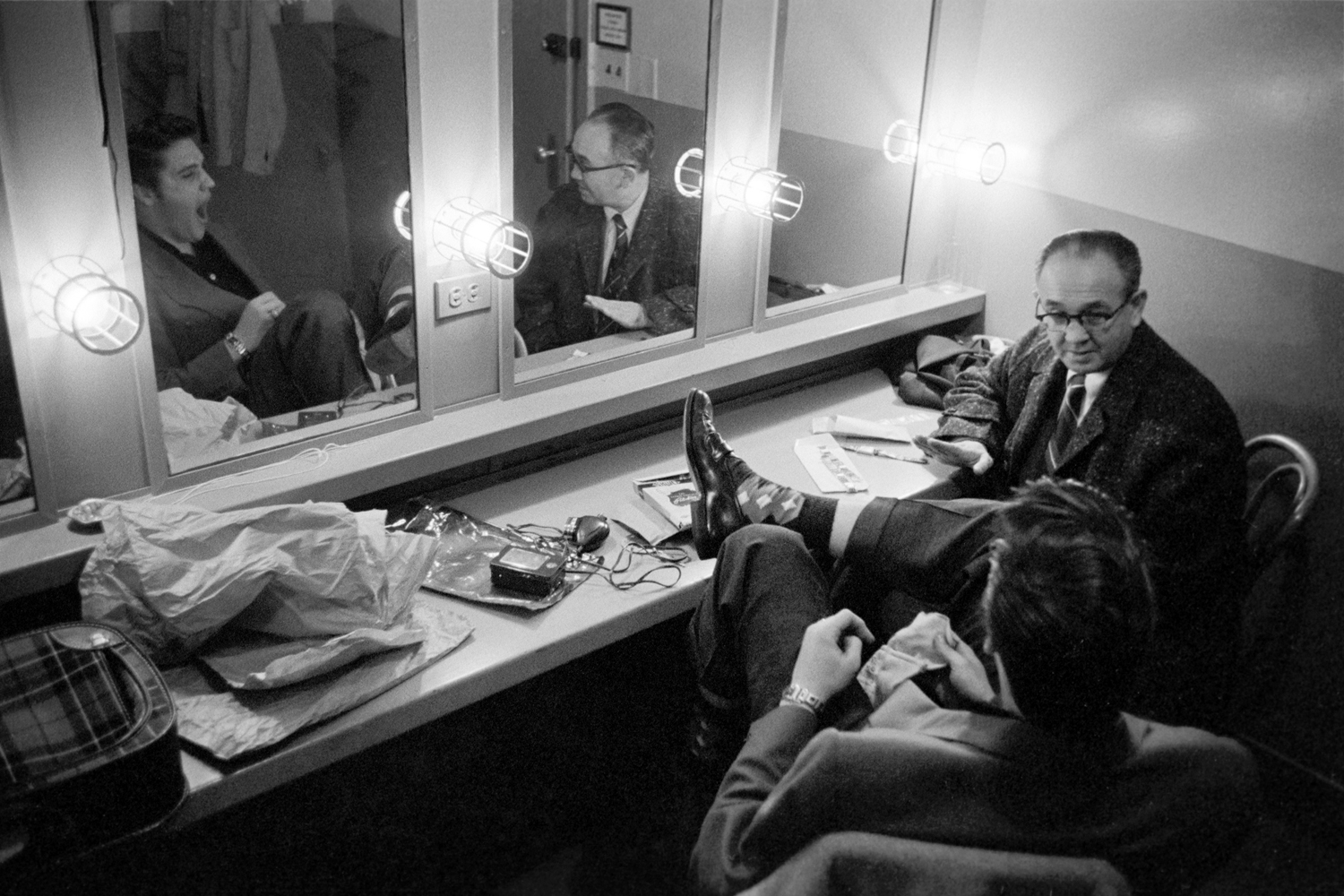 March 17, 1956. Backstage at the Dorsey Brothers 'Stage Show' rehearsal. One of my first pictures of Elvis. He kept looking at a good luck ring on his left hand that he ordered two weeks before on the same show from the ring salesman (sitting next to him). The salesman proceeded to try to persuade him that he needed two more rings. Elvis said no.