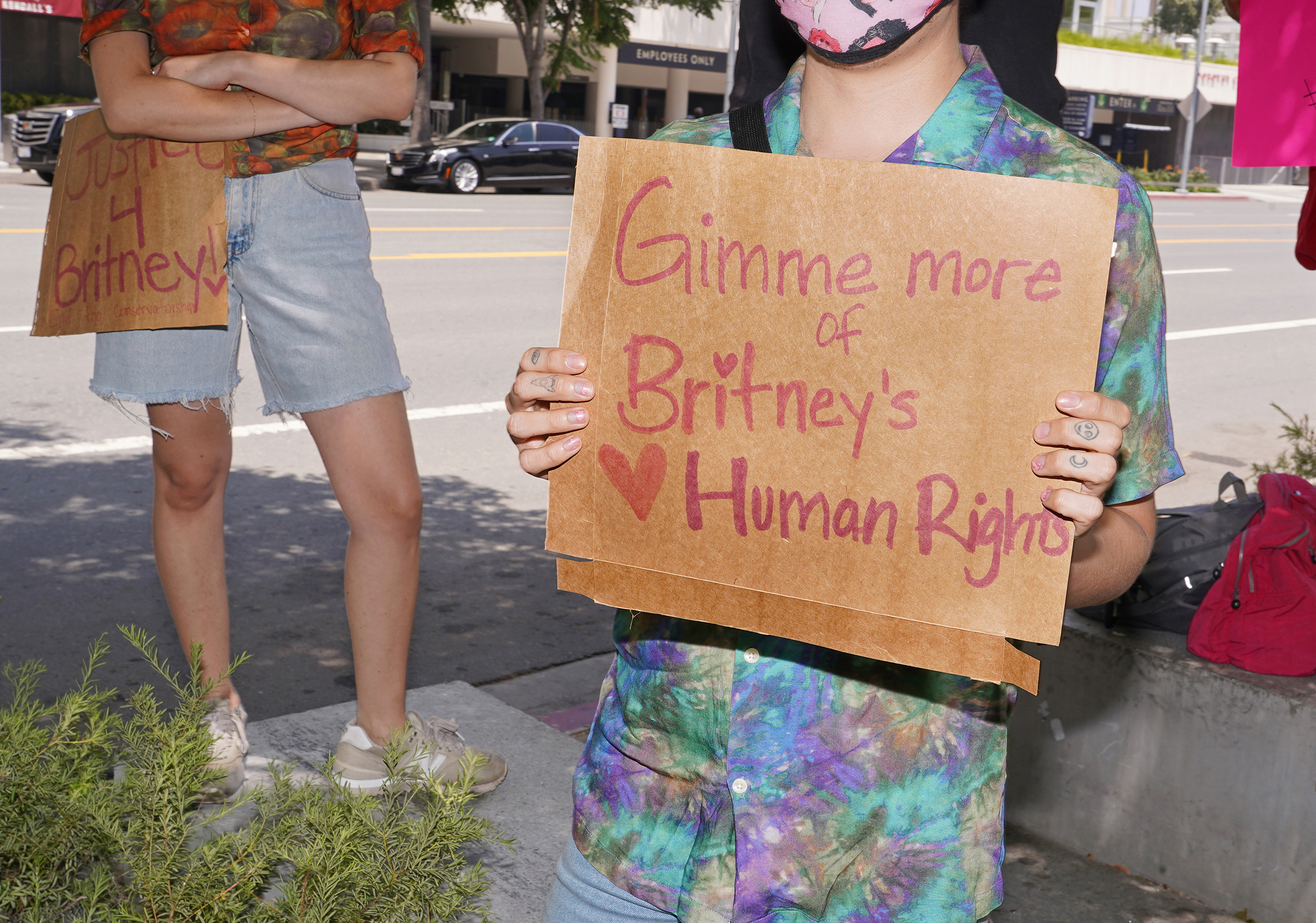 A protester holds a sign that references Britney Spears' song "Gimme More" outside a conservatorship hearing in July 2020.