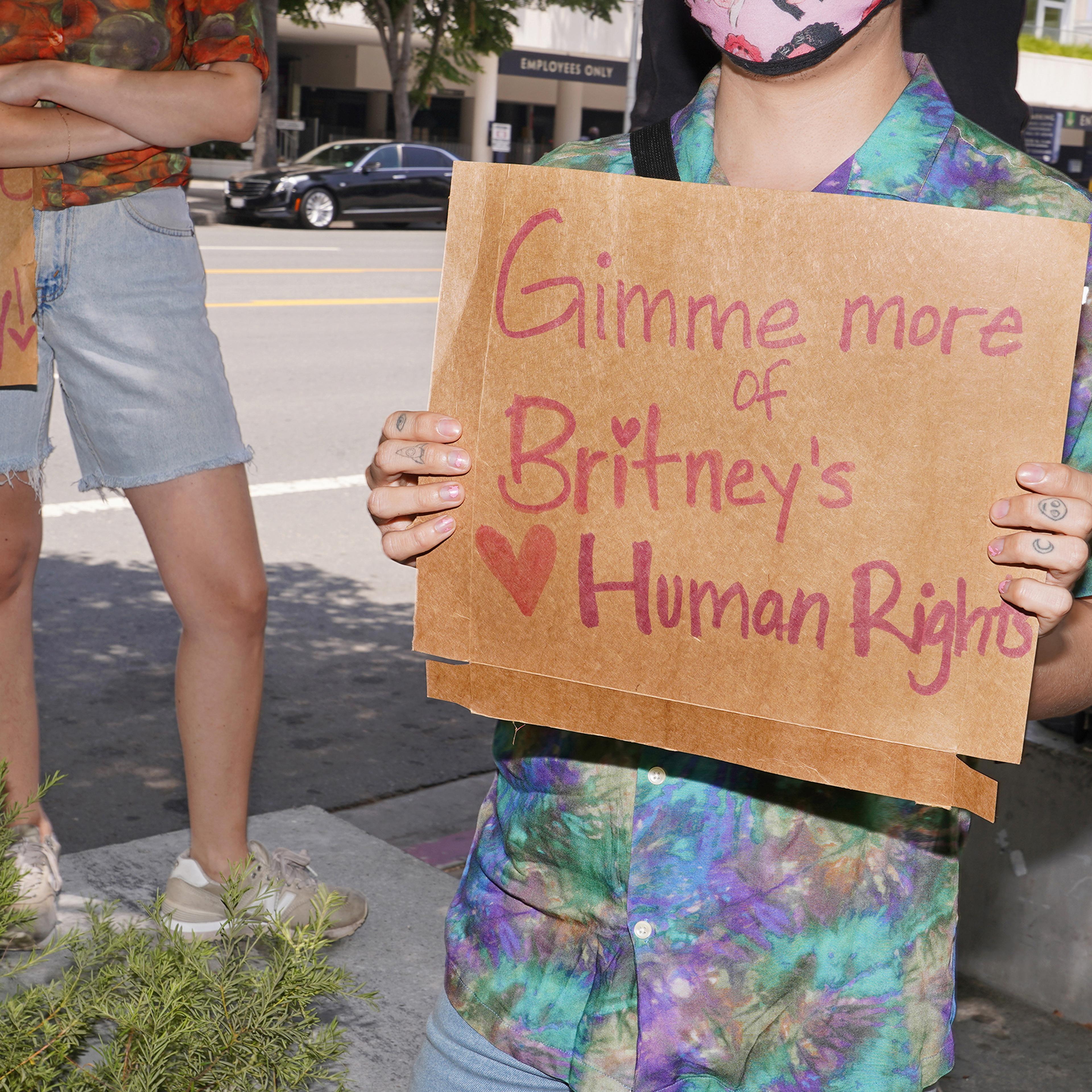 A protester holds a sign that references Britney Spears' song "Gimme More" outside a conservatorship hearing in July 2020.