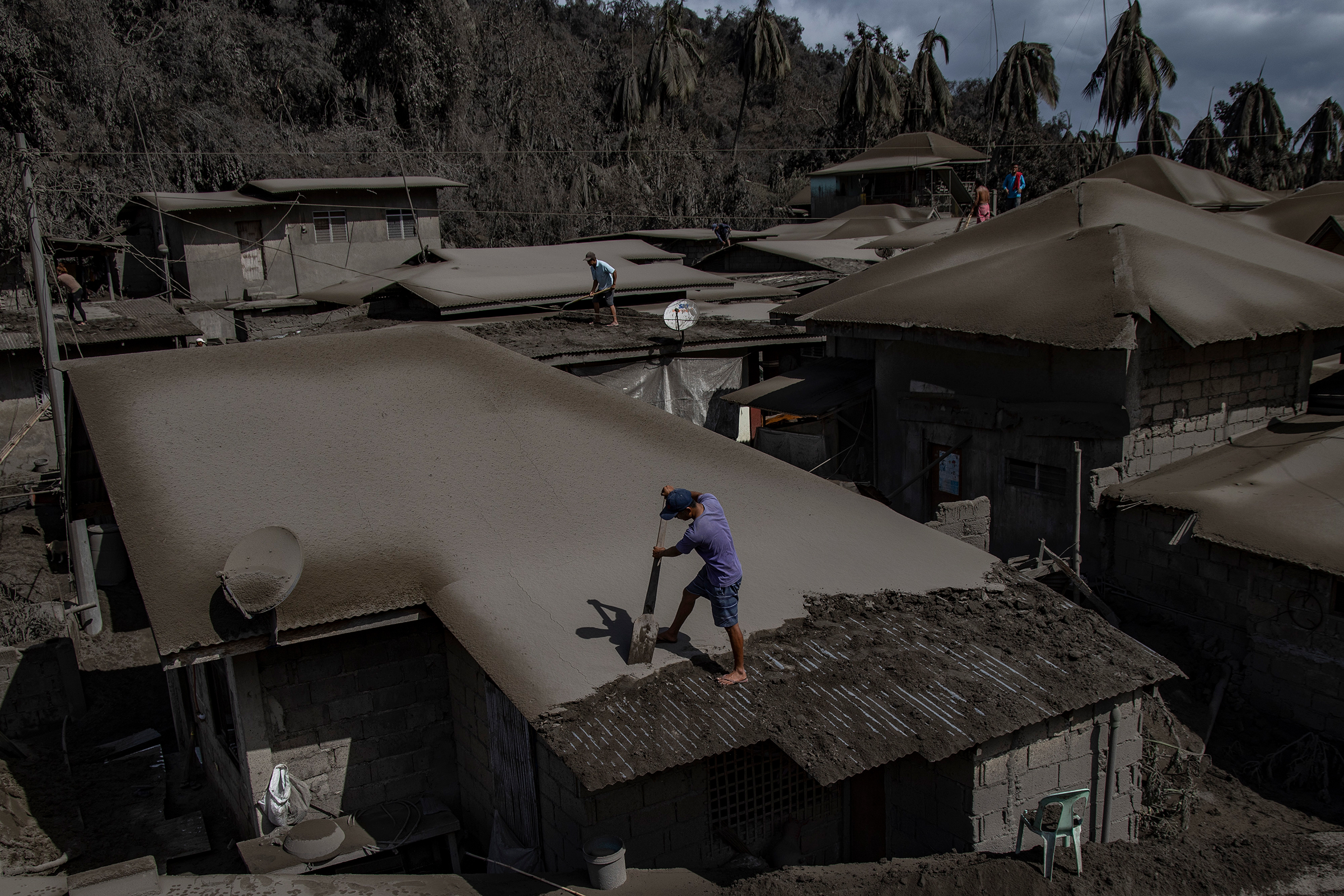 Men clean rooftops of volcanic ash from the recent eruption.