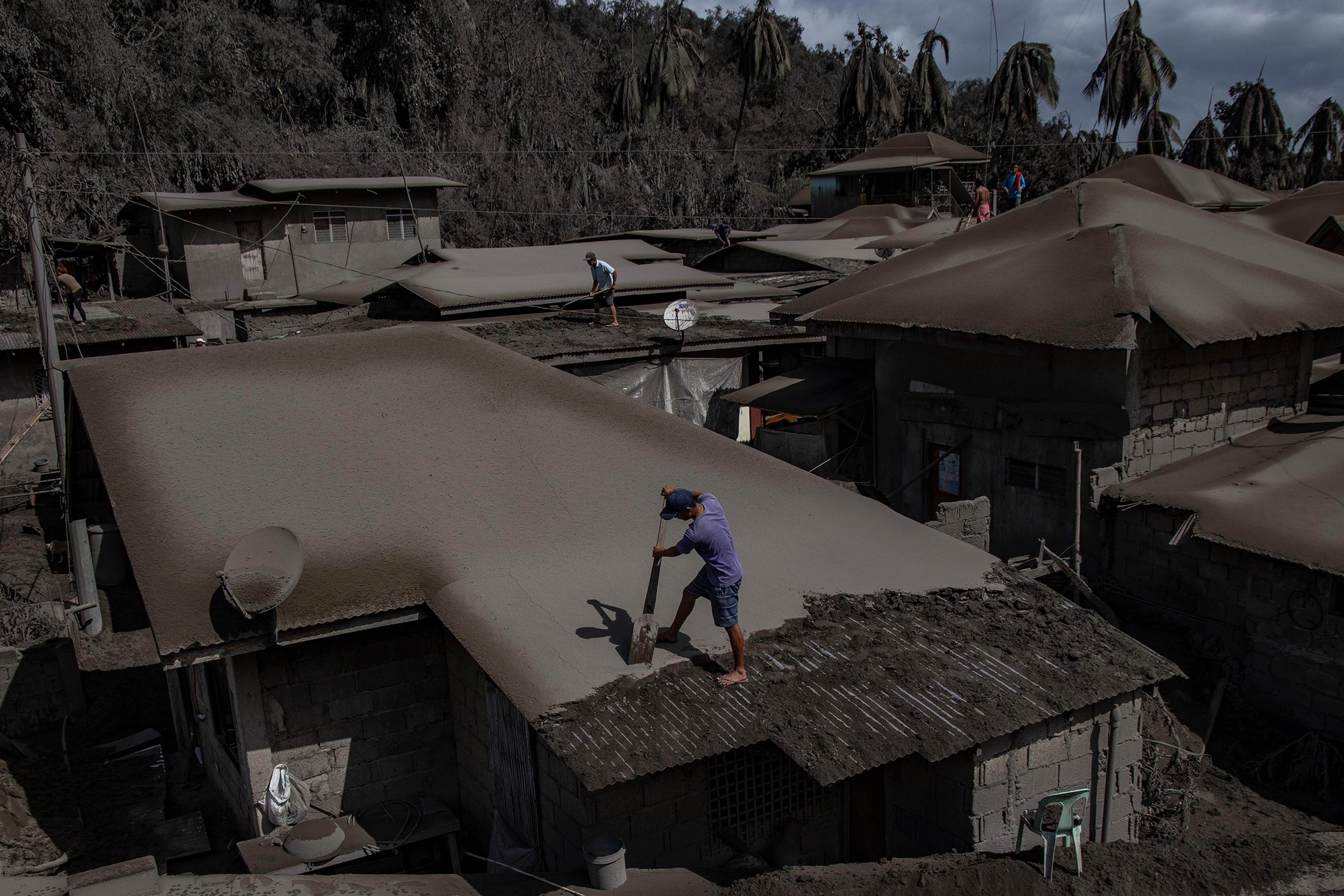 Men clean rooftops of volcanic ash from the recent eruption.