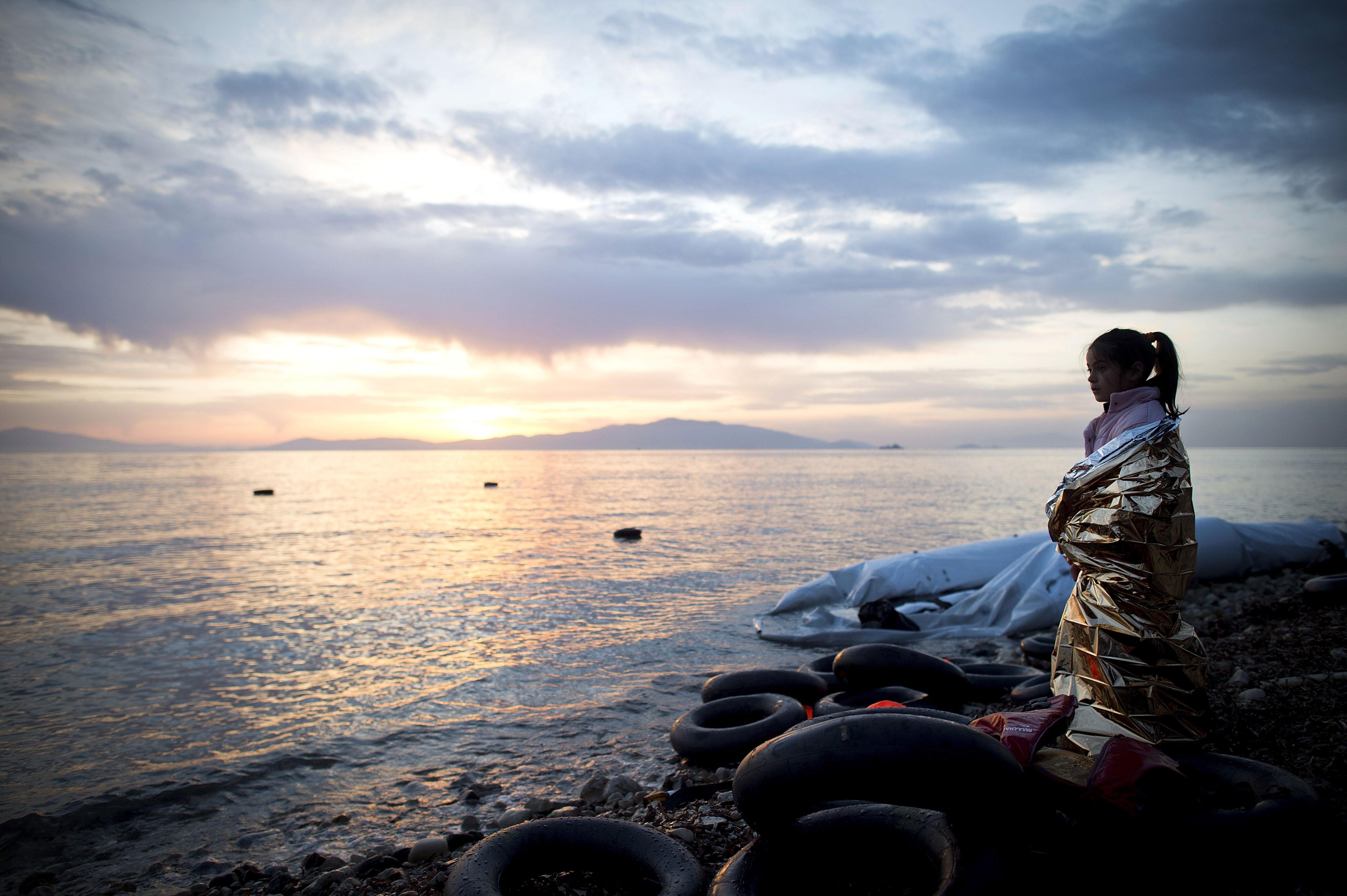 A Syrian girl looks on during sunrise after arriving on an inflatable boat with other refugees, crossing the sea from Turkey to Lesbos, some 5 kilometres south of the capital of the Island, Mytelene on March 9, 2016. Turkey has announced today to take ba