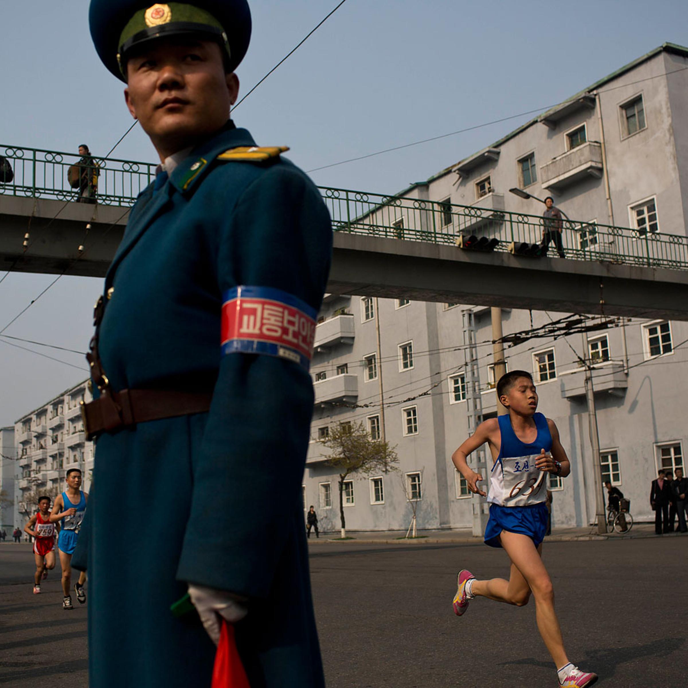 Runners pass under a pedestrian bridge in central Pyongyang during the running of the Mangyongdae Prize International Marathon in Pyongyang, on April 13, 2014.