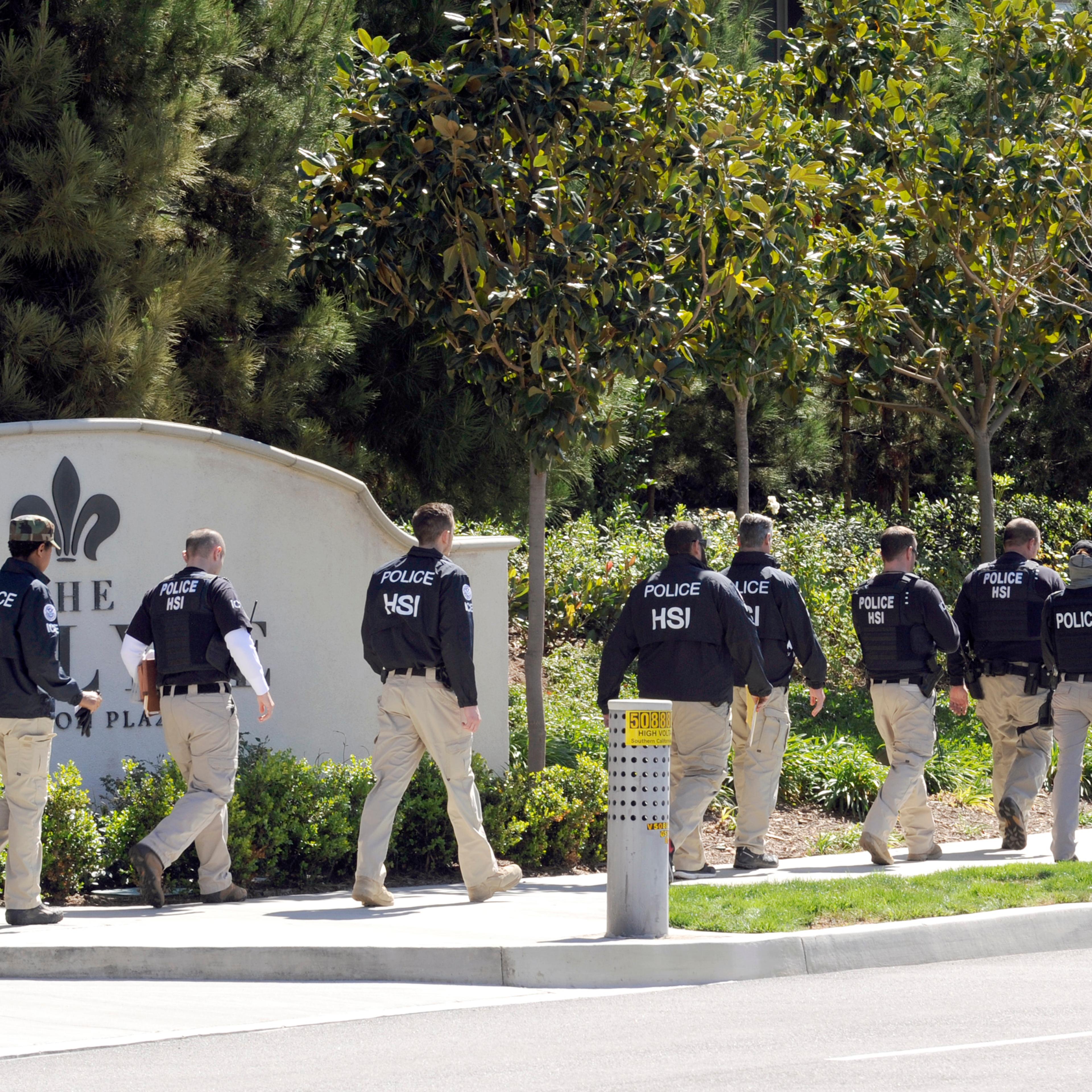 Federal agents walk past the Carlyle Apartments, the location of a suspected "baby tourism operation," in Irvine, Calif. on March 3, 2015.