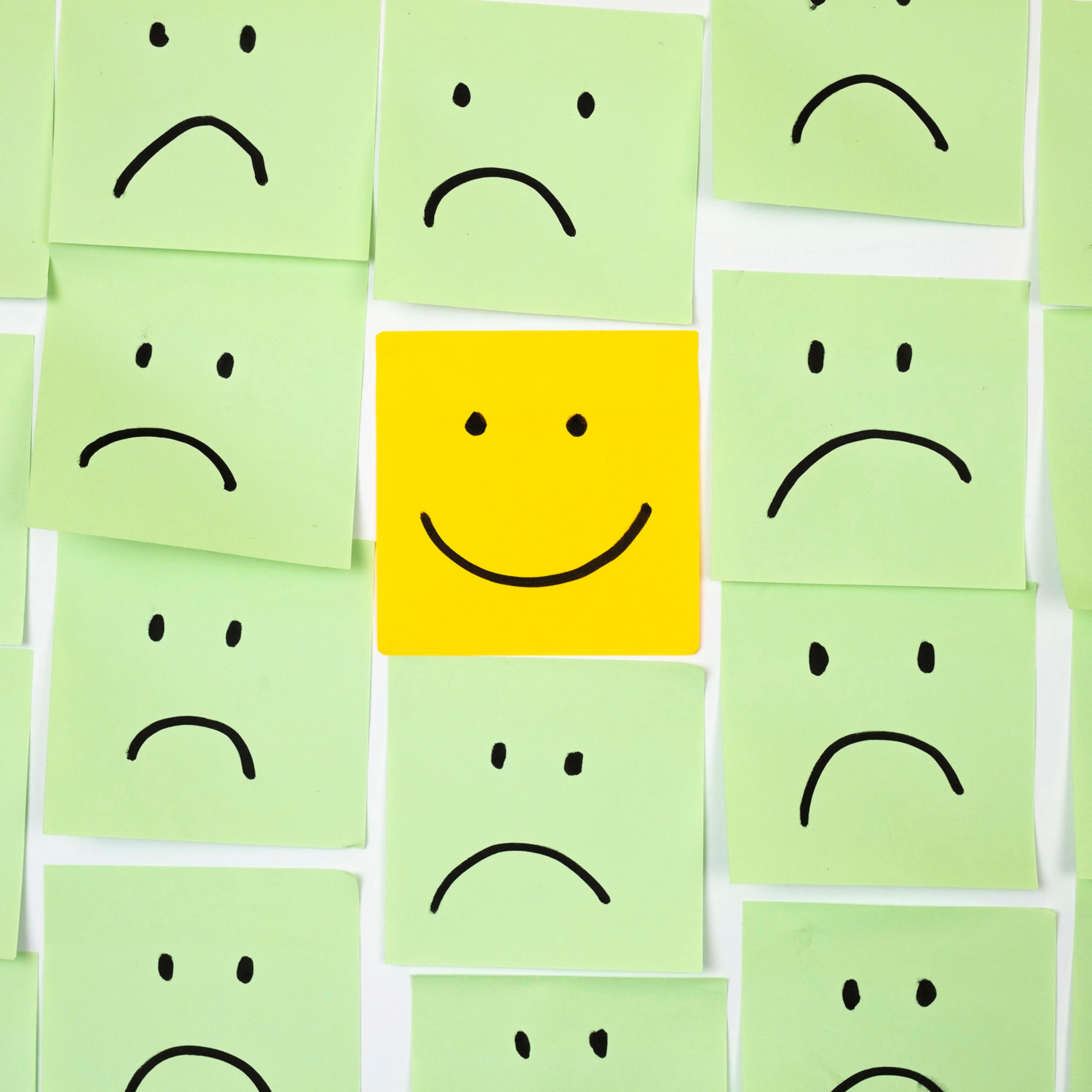 Sad faces on sticky notes with one happy one