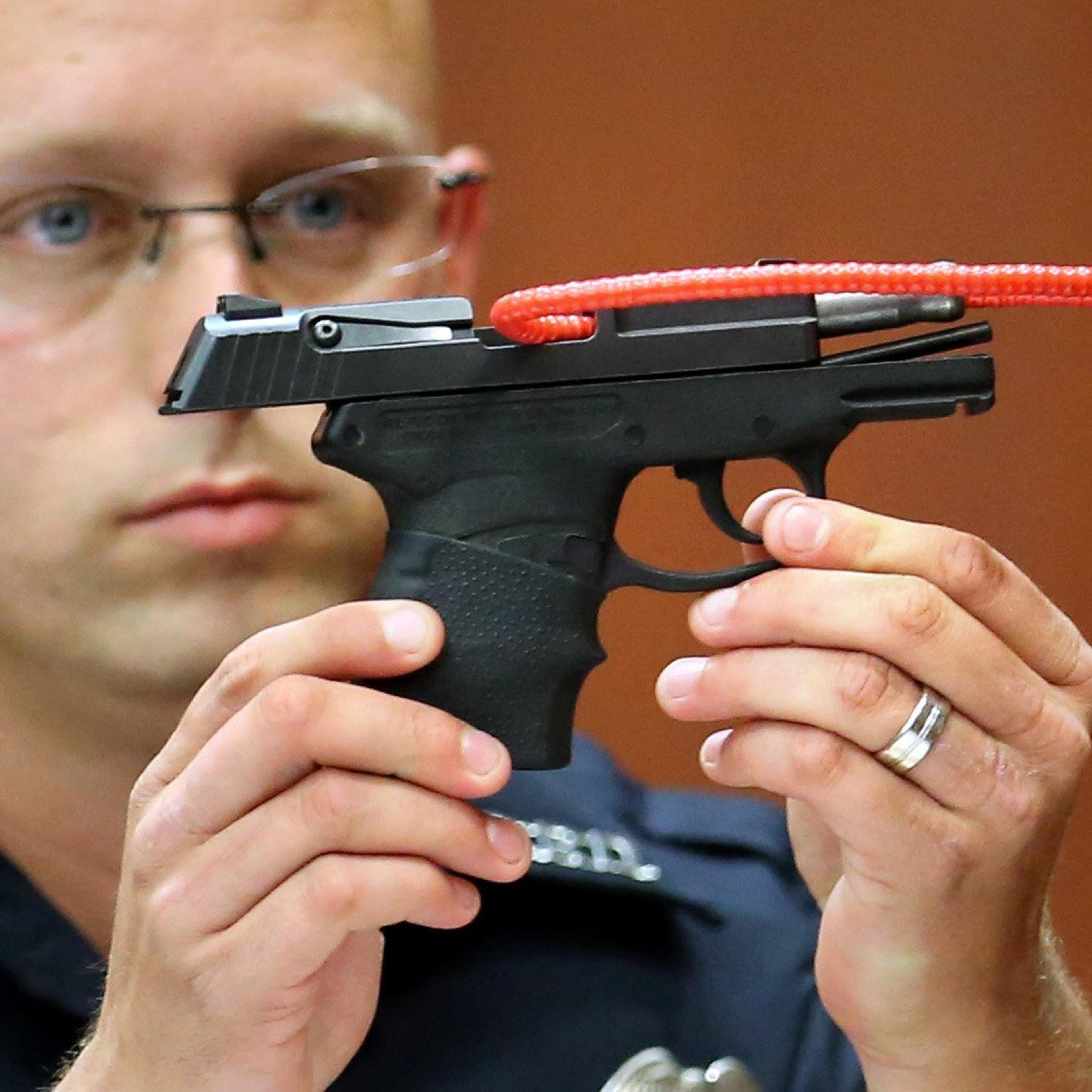 Sanford police officer Timothy Smith holds up the gun that was used to kill Trayvon Martin, while testifying in the 15th day of the George Zimmerman trial, in Seminole circuit court in Sanford, Florida, Friday, June 28, 2013.
