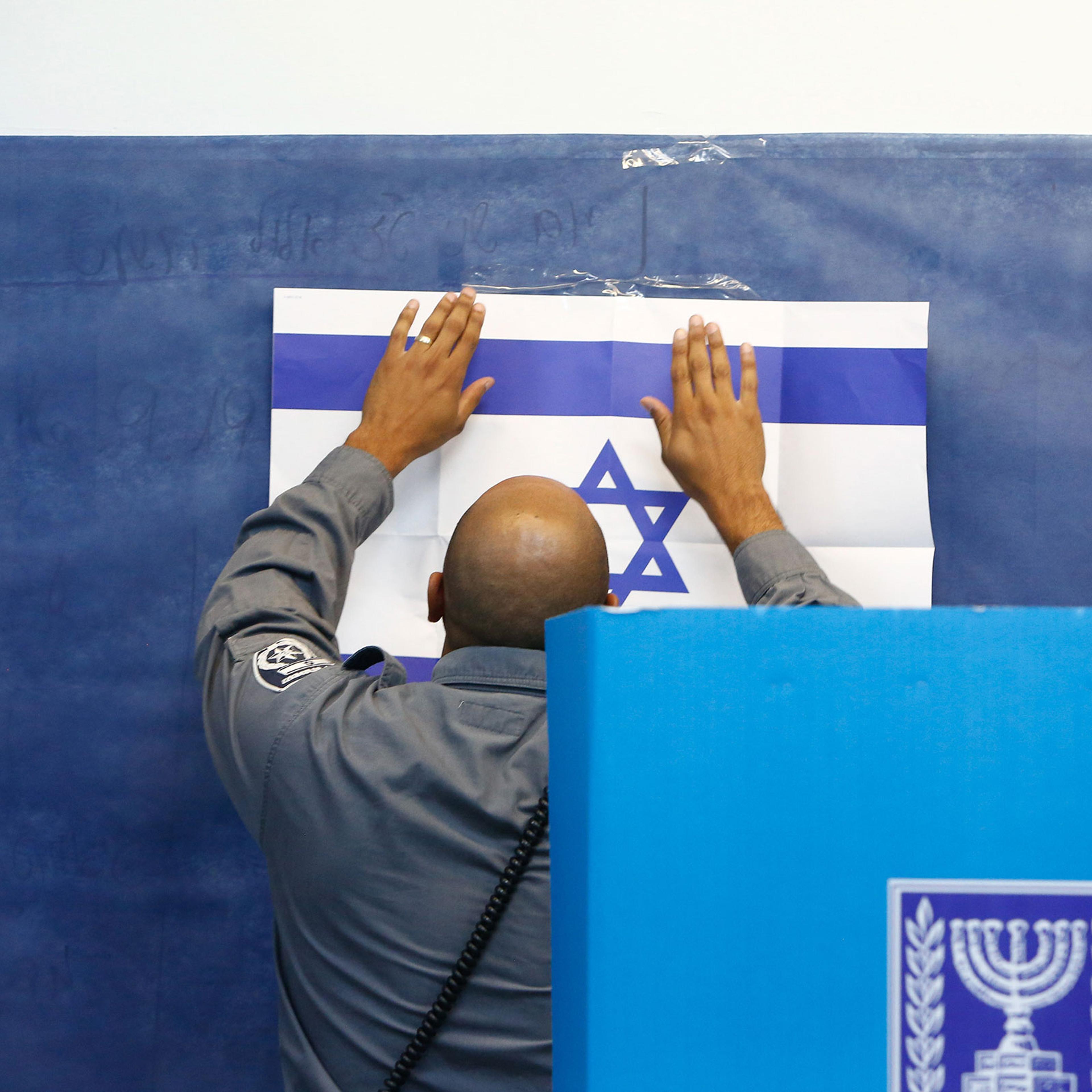 An official adjusts a poster of the Israeli flag at a polling station in Rosh Haayin, Israel, on Sept. 17, 2019.
