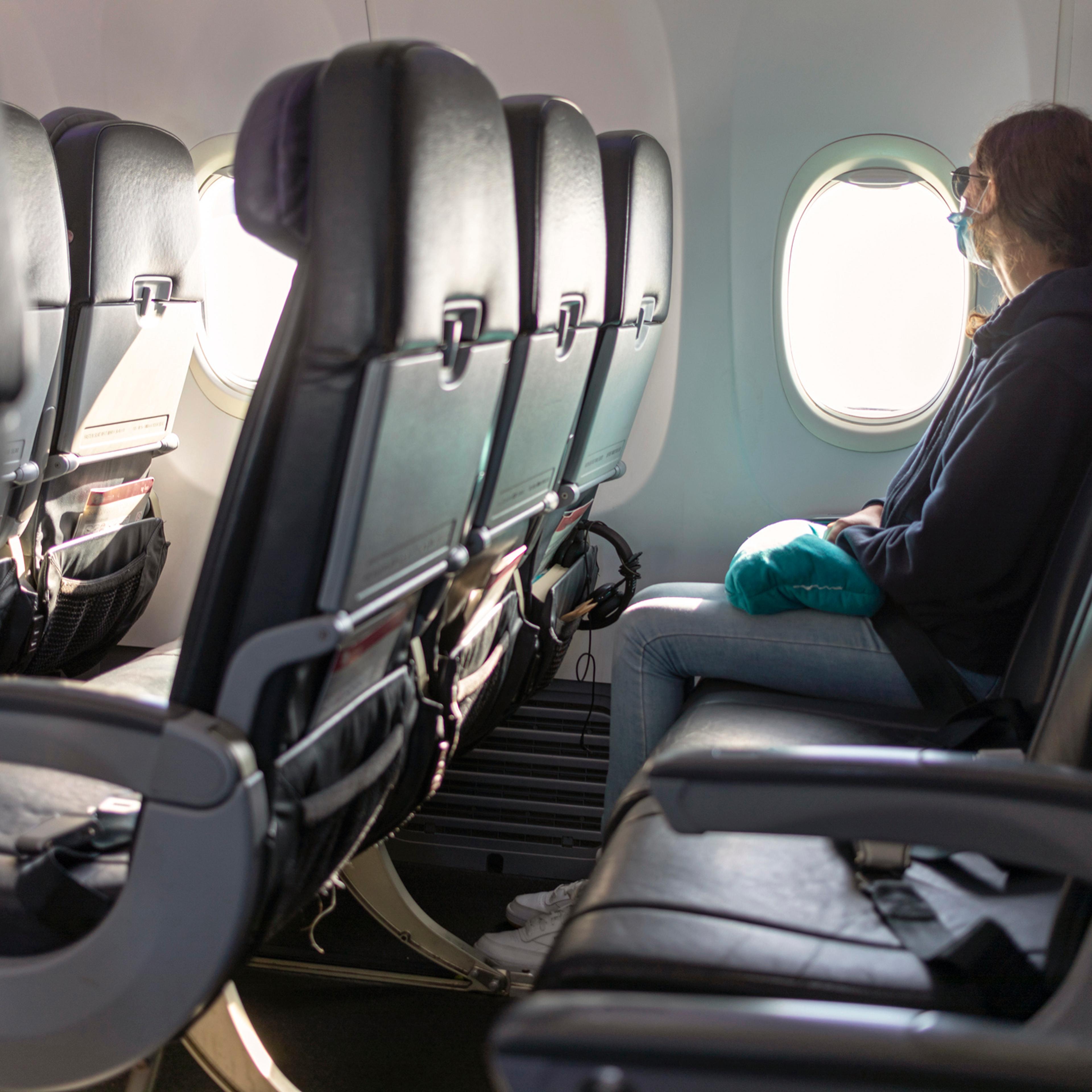 Air travel, passenger looking out airplane window, empty seats, COVID-19