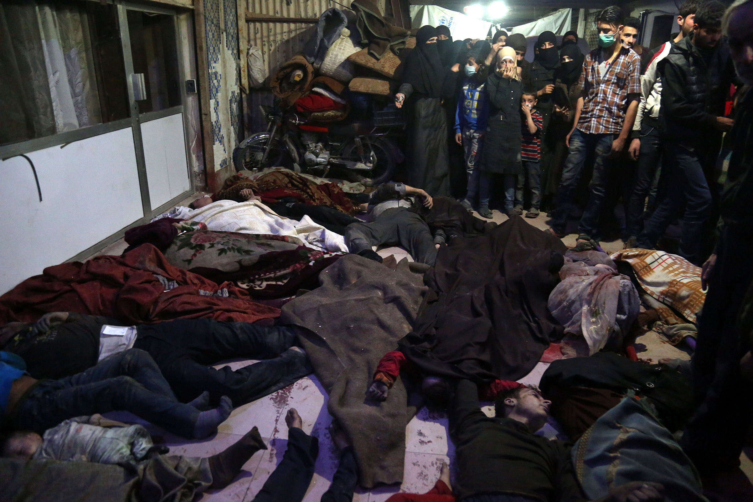 Survivors and medical workers survey victims of the suspected chemical-weapons attack