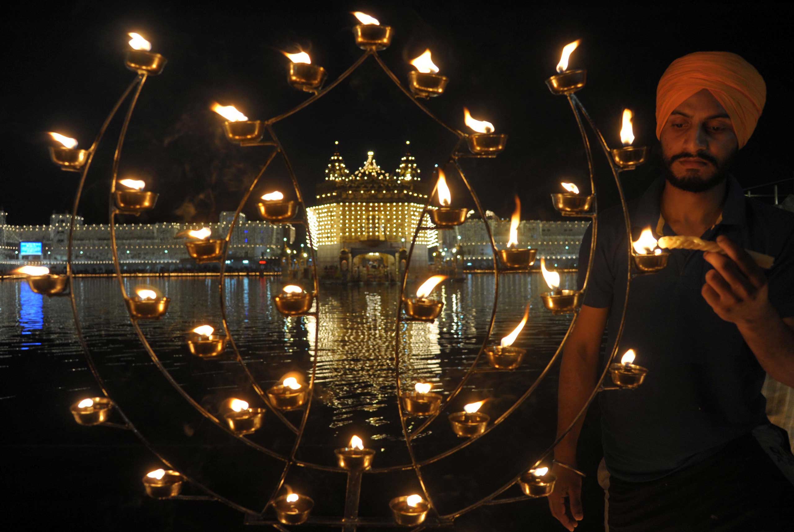 An Indian Sikh devotee lights candles on the occasion of Bandi Chhor Divas, or Diwali, at the illuminated Golden Temple in Amritsar, India on Oct. 23, 2014.