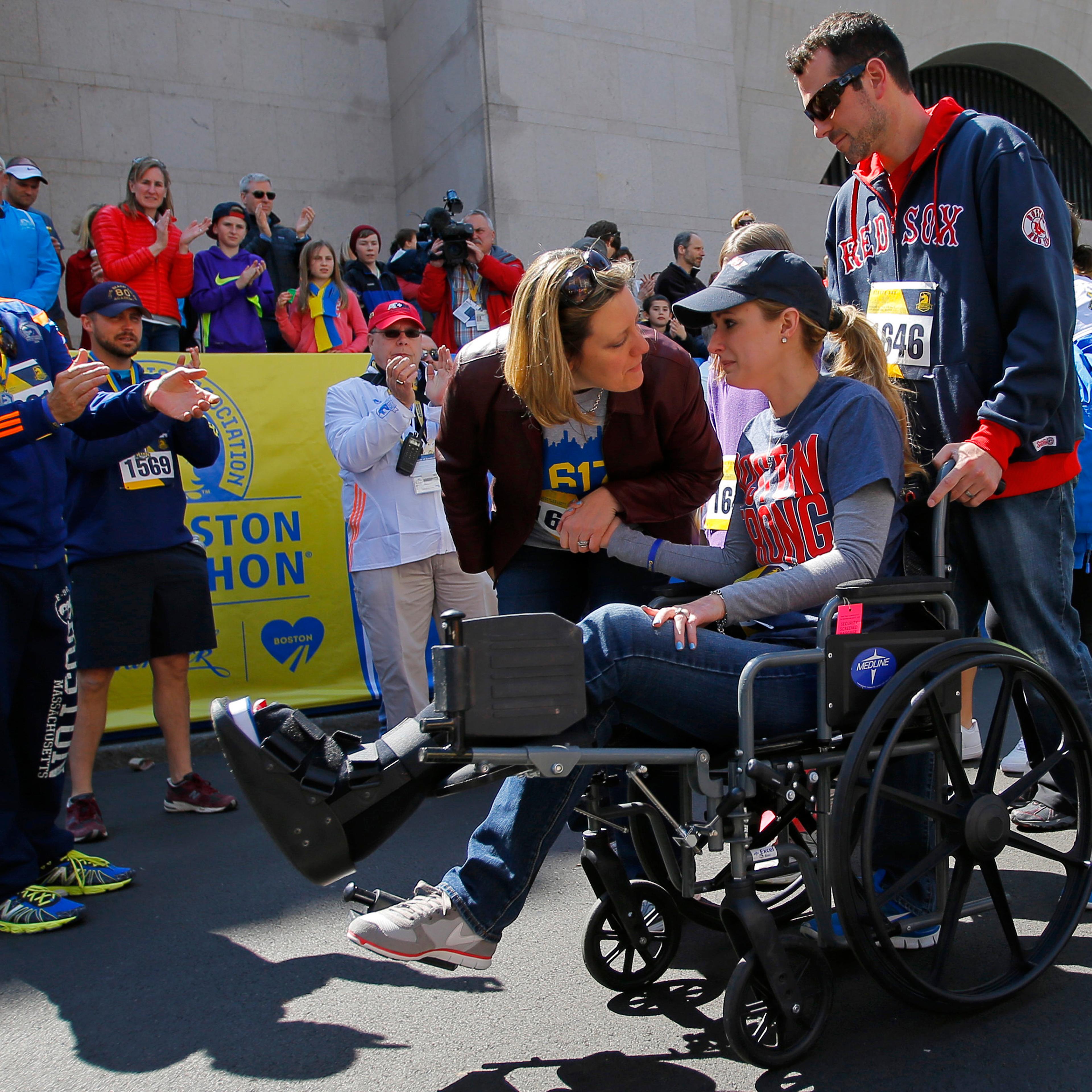 Actor Kevin Spacey (L) cheers on as 2013 Boston Marathon bombing survivor Rebekah Gregory DiMartino (2nd R) crosses the marathon finish line during a Tribute Run for survivors and first responders in Boston on April 19, 2014.