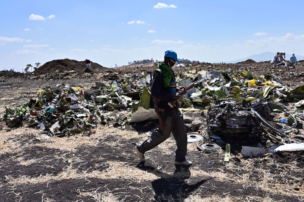 An Oromo man hired to assist forensic investigators walks by a pile of twisted airplane debris at the crash site of an Ethiopian airways operated Boeing 737 MAX aircraft on March 16, 2019 at Hama Quntushele village near Bishoftu in Oromia region
