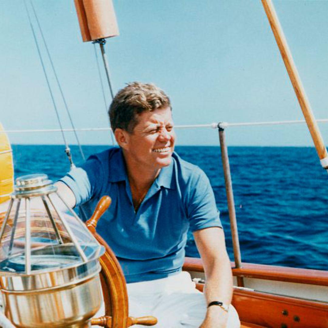 President Vacations at Hammersmith Farm. President Kennedy at the wheel of the Coast Guard Yacht "Manitou". Narragansett Bay, RI. 26 August 1962
