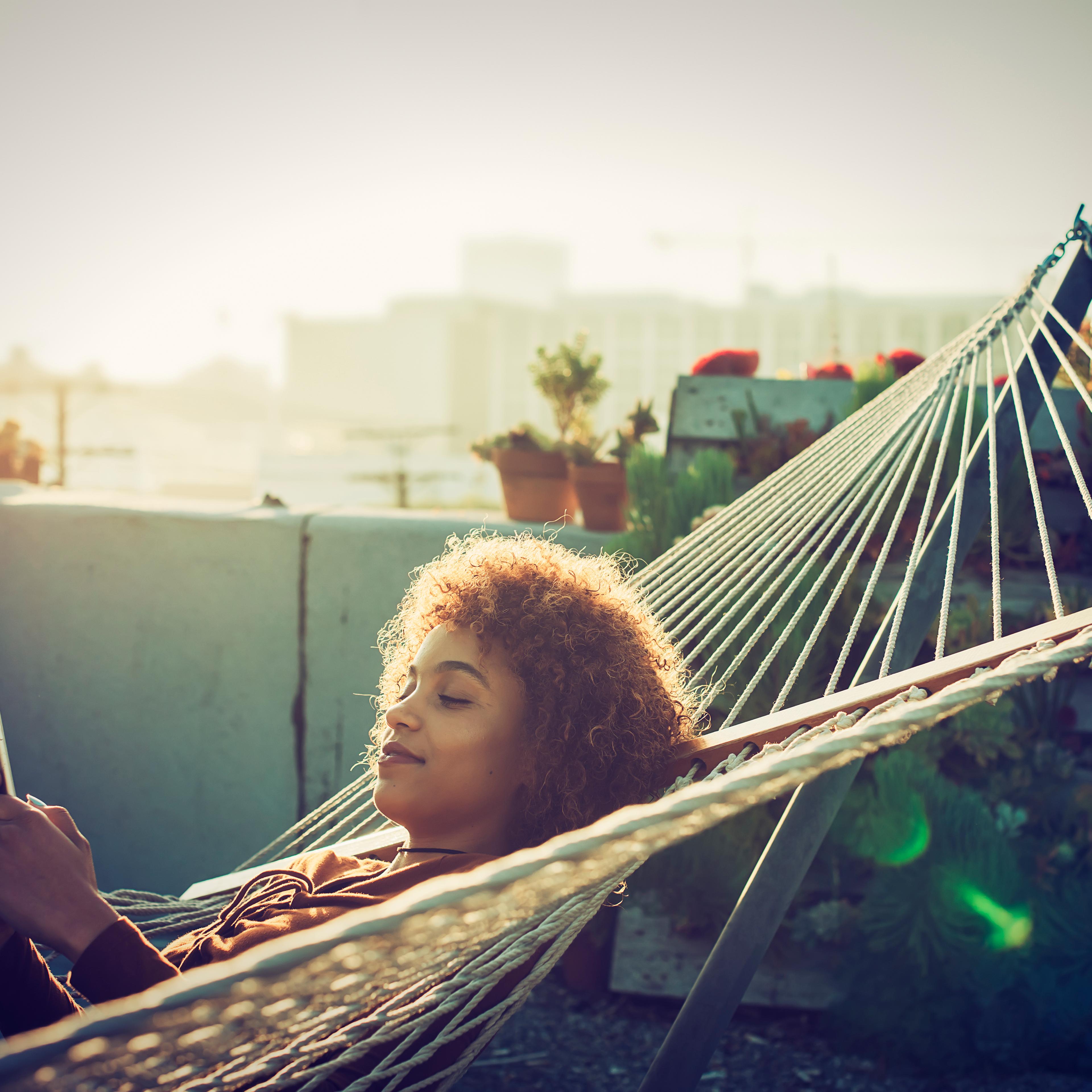 Young woman checks smartphone from hammock