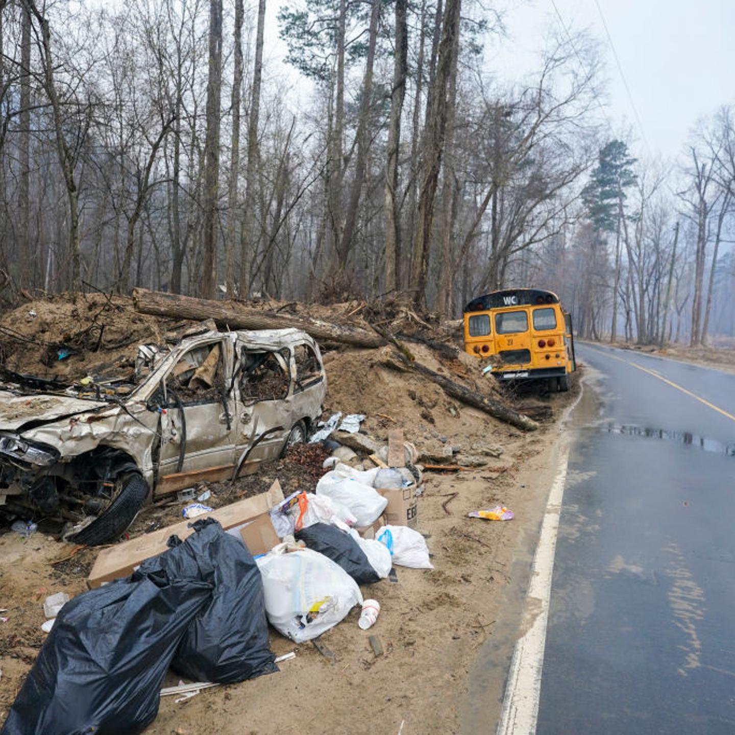 Debris from Hurricane Helene litters the side of the road as smoke hangs in the air near the Black Cove wildfire on March 24, 2025 in Polk County, North Carolina. Three large wildfires have burned more than 3,000 acres as evacuation orders were issued fo