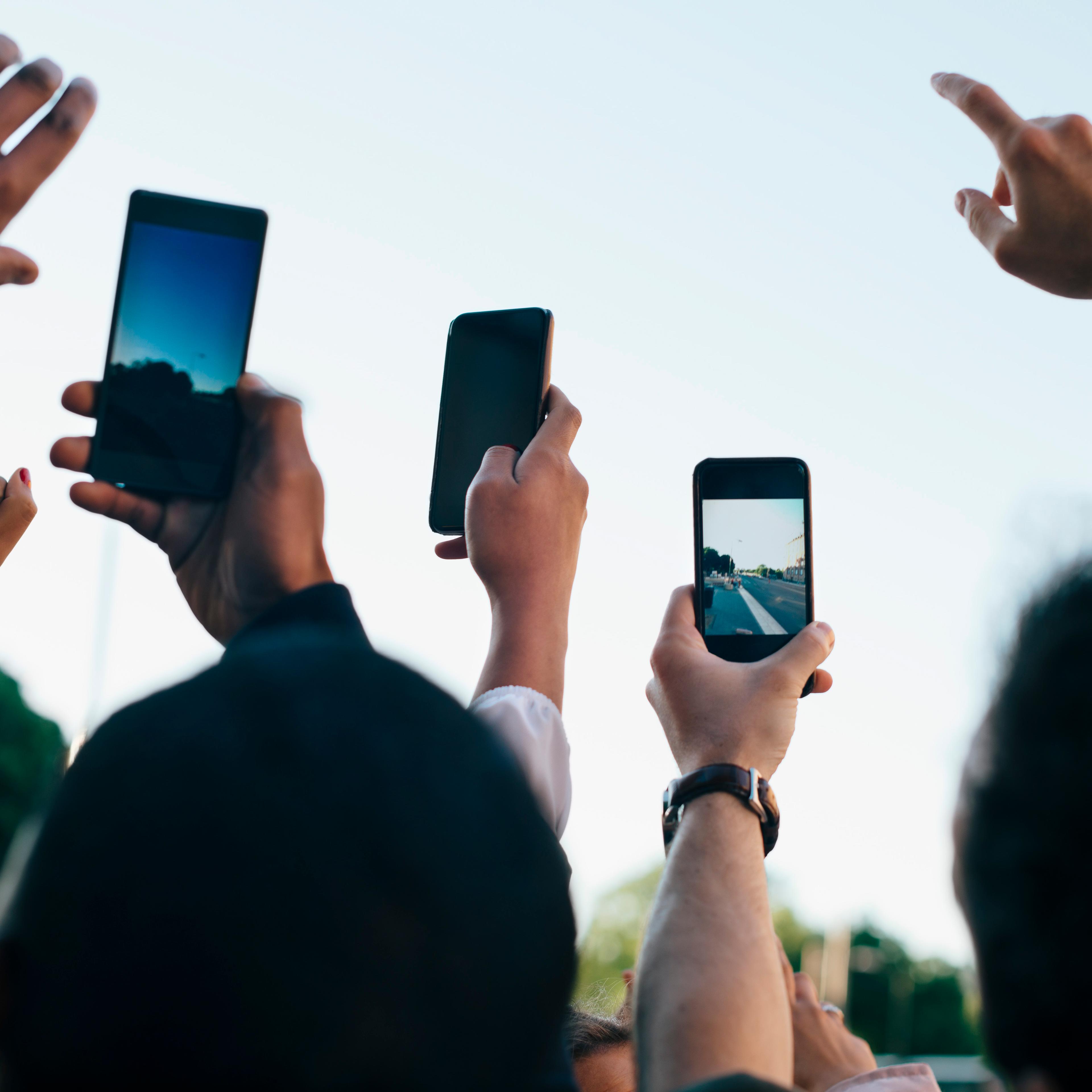 A group of friends photographing the sky with smartphones