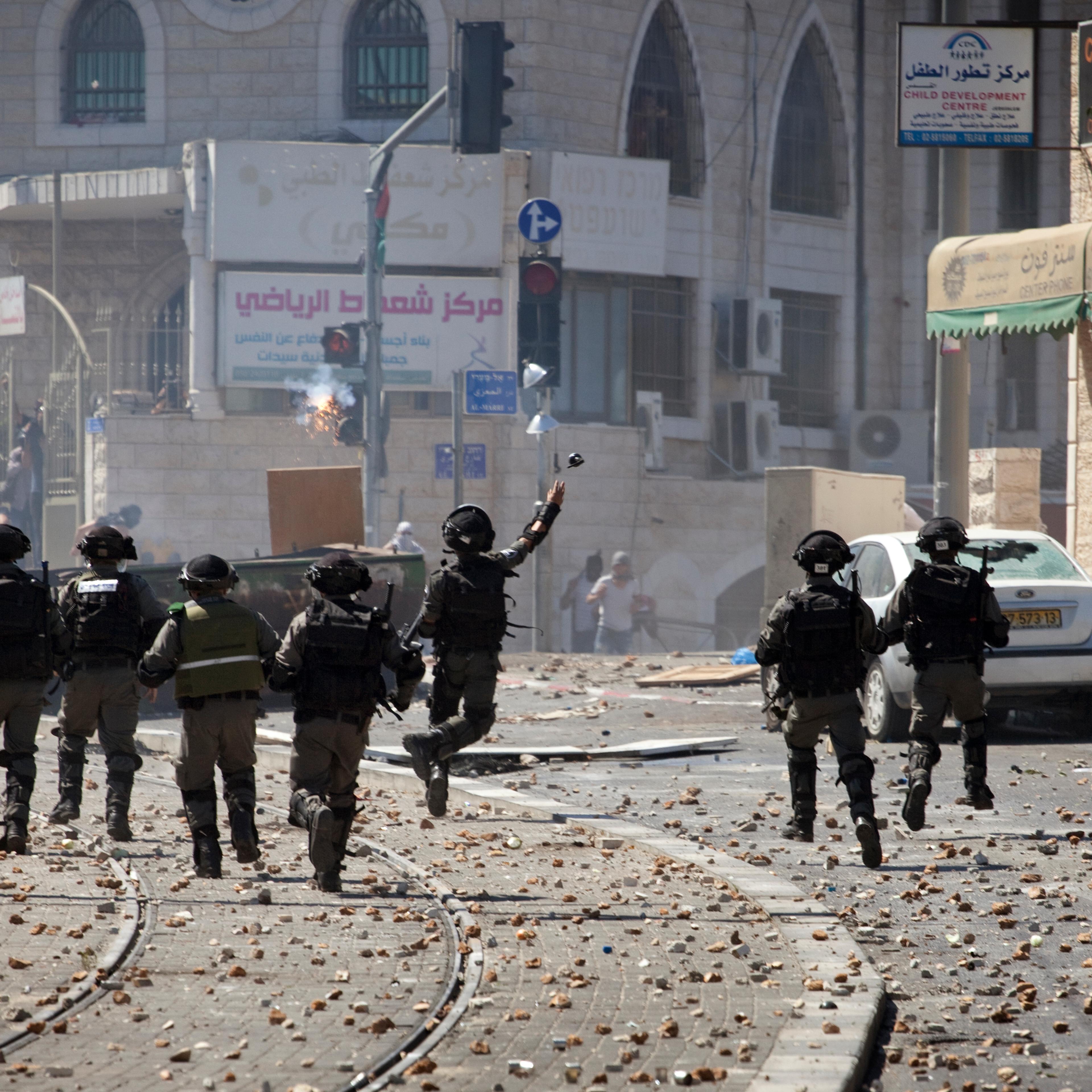 An Israeli soldier throws a grenade during clashes with