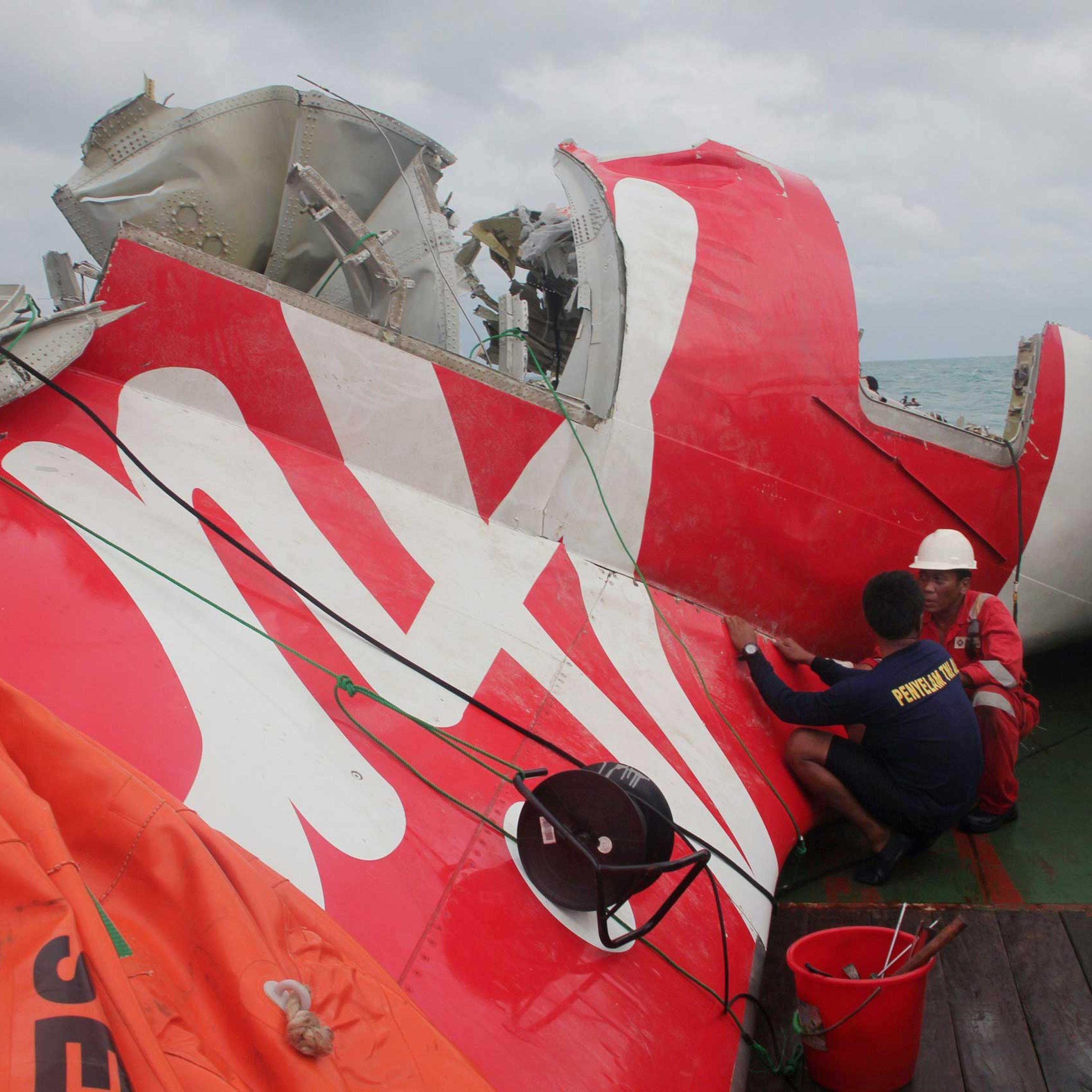An Indonesian diver and an official examine the wreckage from AirAsia flight QZ8501 after it was lifted into the Crest Onyx ship at sea, near Indonesia on Jan. 10, 2015.