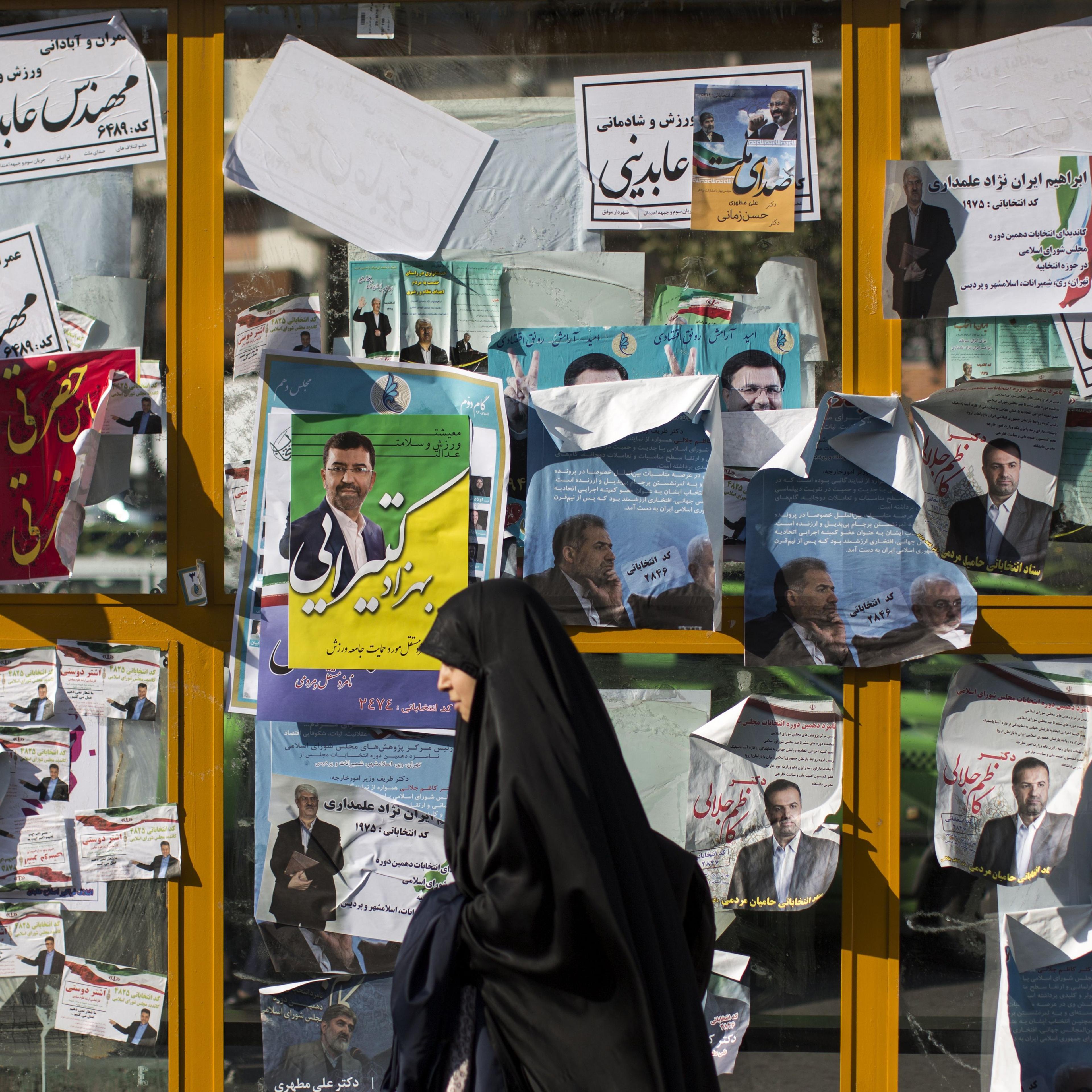 An Iranian woman walks past electoral posters for upcoming parliamentary elections in downtown Tehran on Feb. 25, 2016.