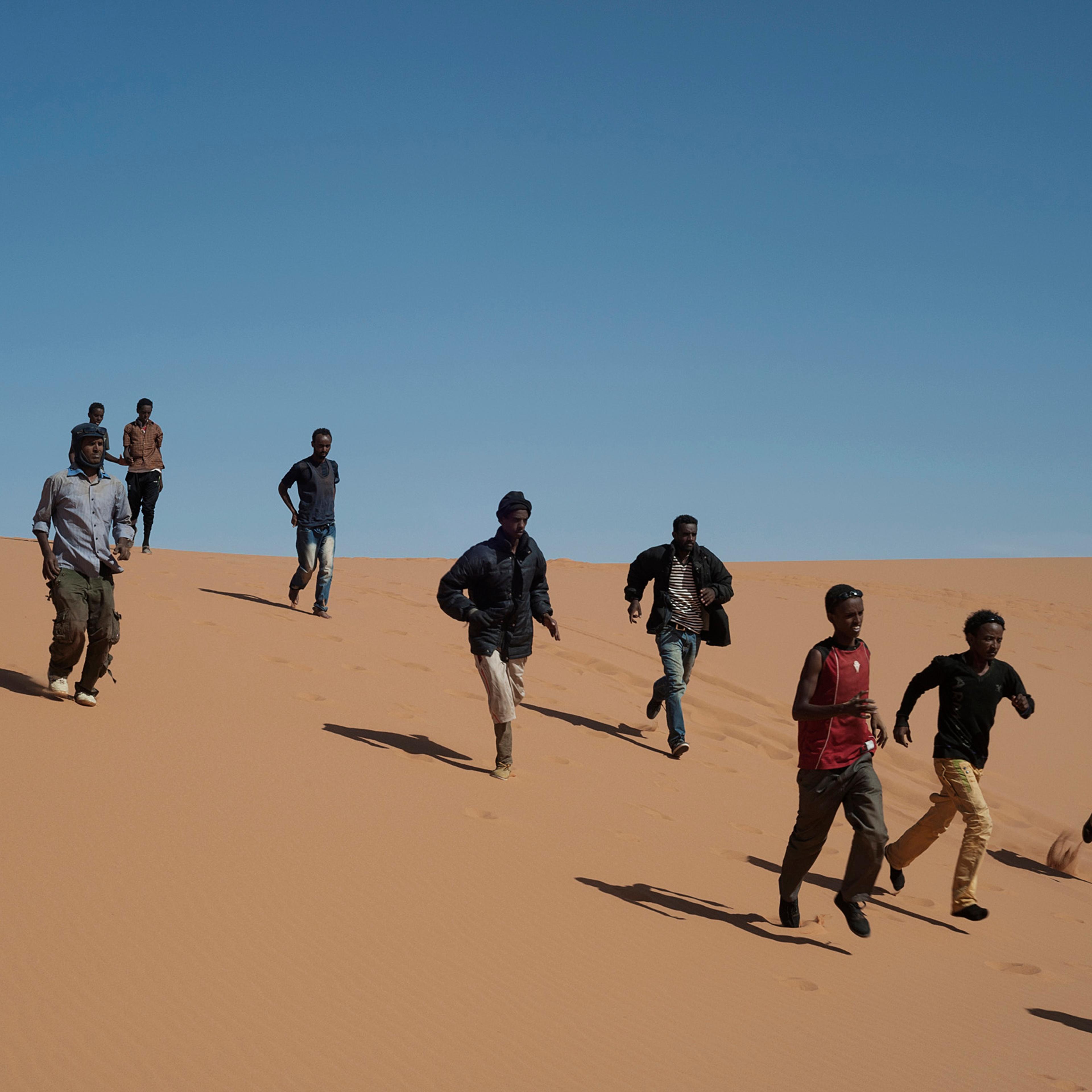 Refugees run to reach their transport to continue their journey in Libya, near the border with Egypt, May 18, 2014.