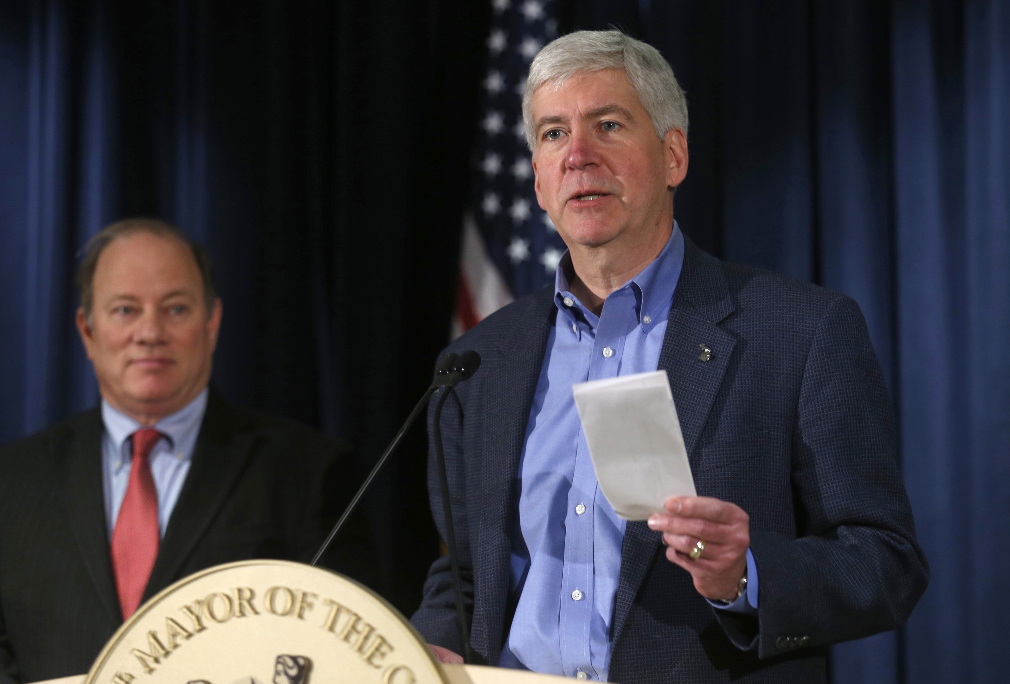 Michigan Governor Rick Snyder holds a rebate check for $1.2 million dollars to hand to Detroit Mayor Mike Duggan during a news conference discussing the city of Detroit exiting from bankruptcy in Detroit