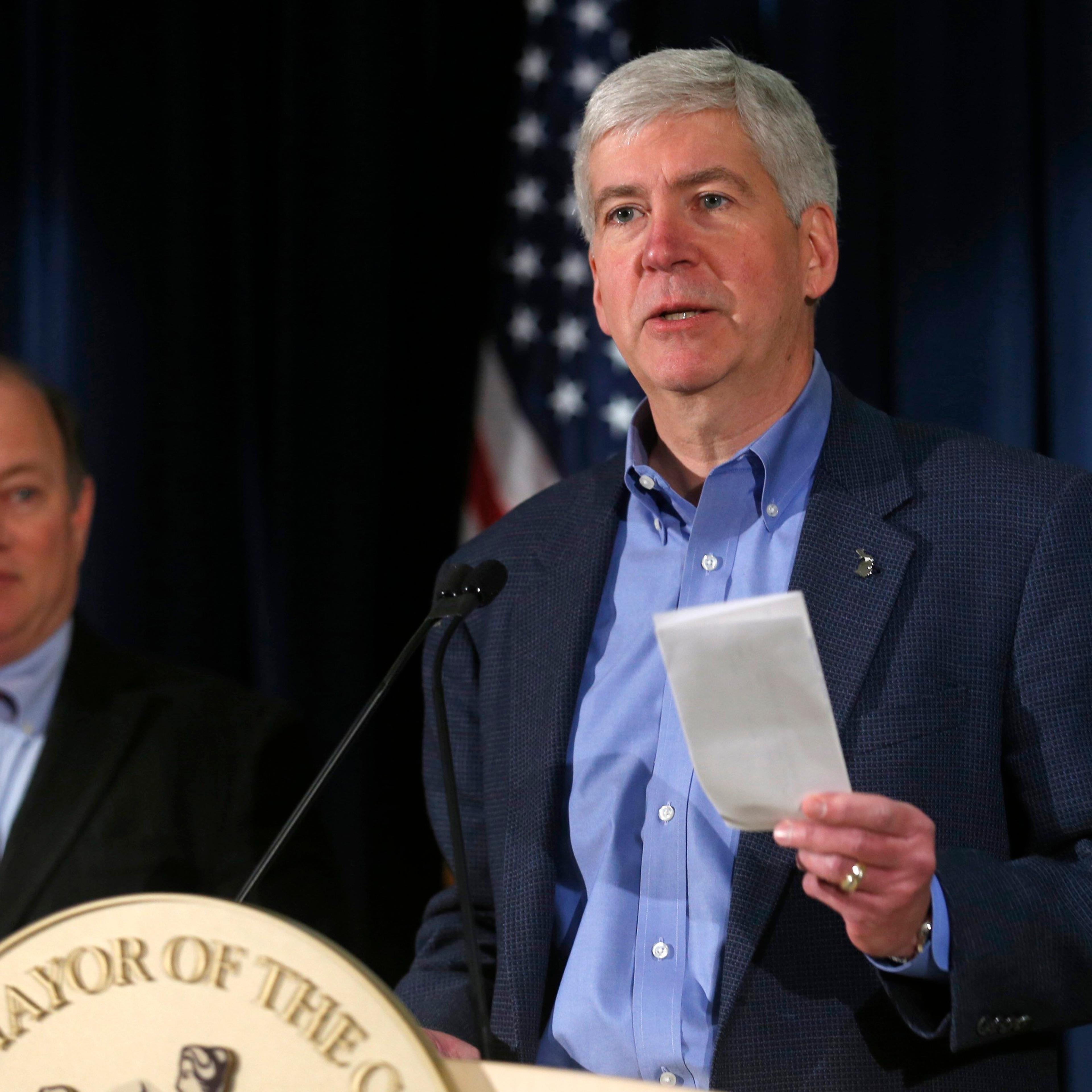 Michigan Governor Rick Snyder holds a rebate check for $1.2 million dollars to hand to Detroit Mayor Mike Duggan during a news conference discussing the city of Detroit exiting from bankruptcy in Detroit