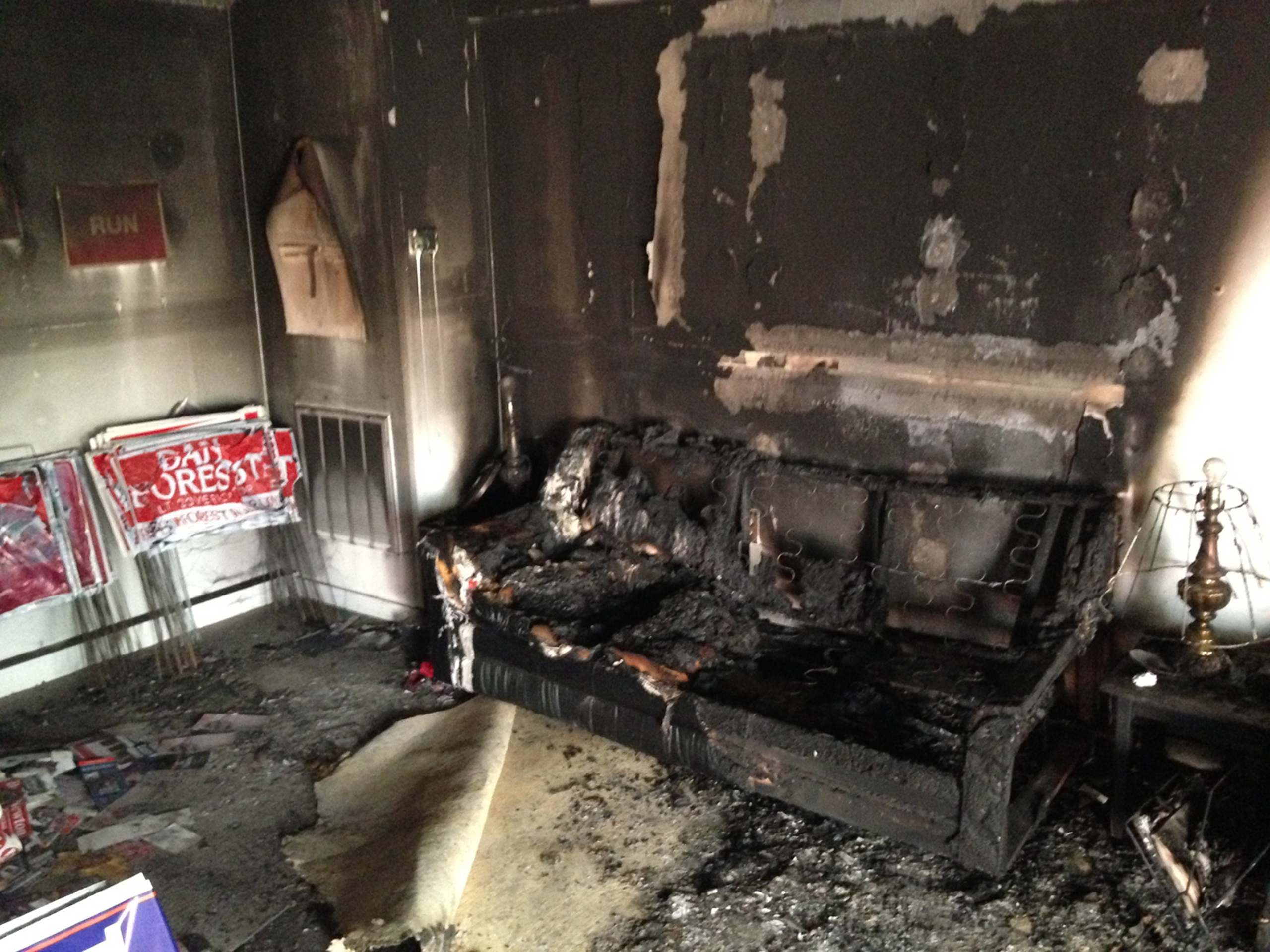 A burnt couch is shown next to warped campaign signs at the Orange County Republican Headquarters in Hillsborough, NC, on Oct. 16 2016.