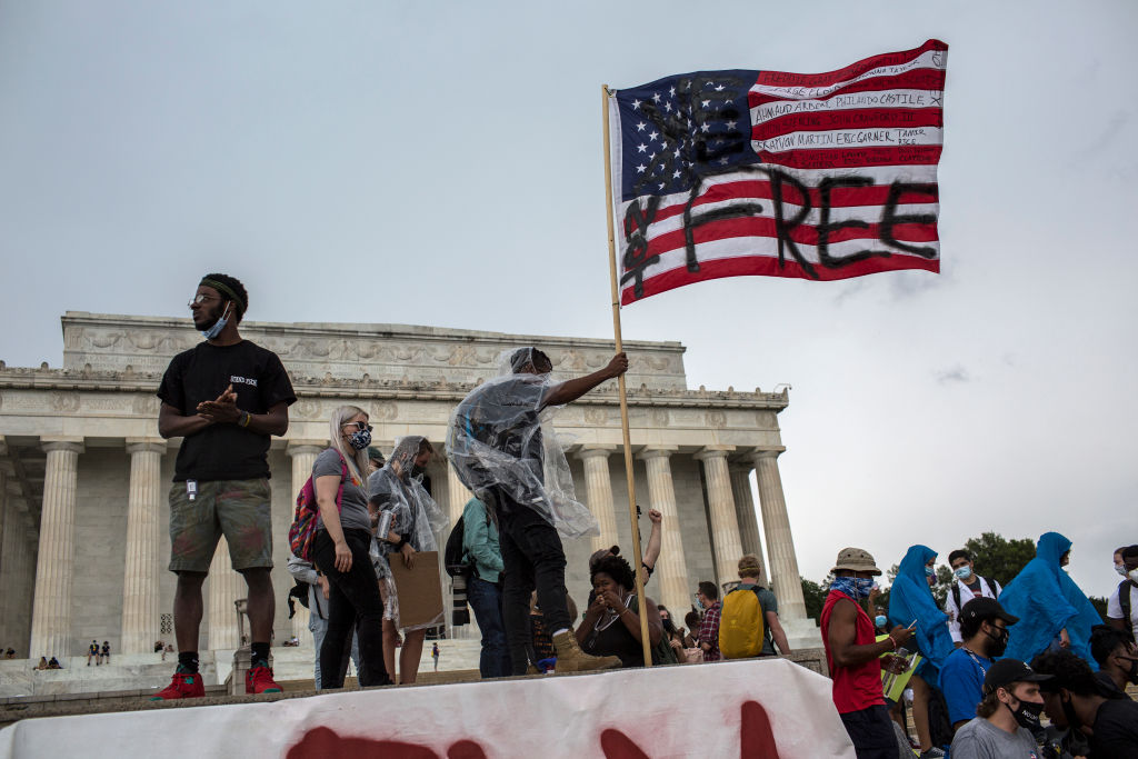A man waves an American flag with the words "Not Free"