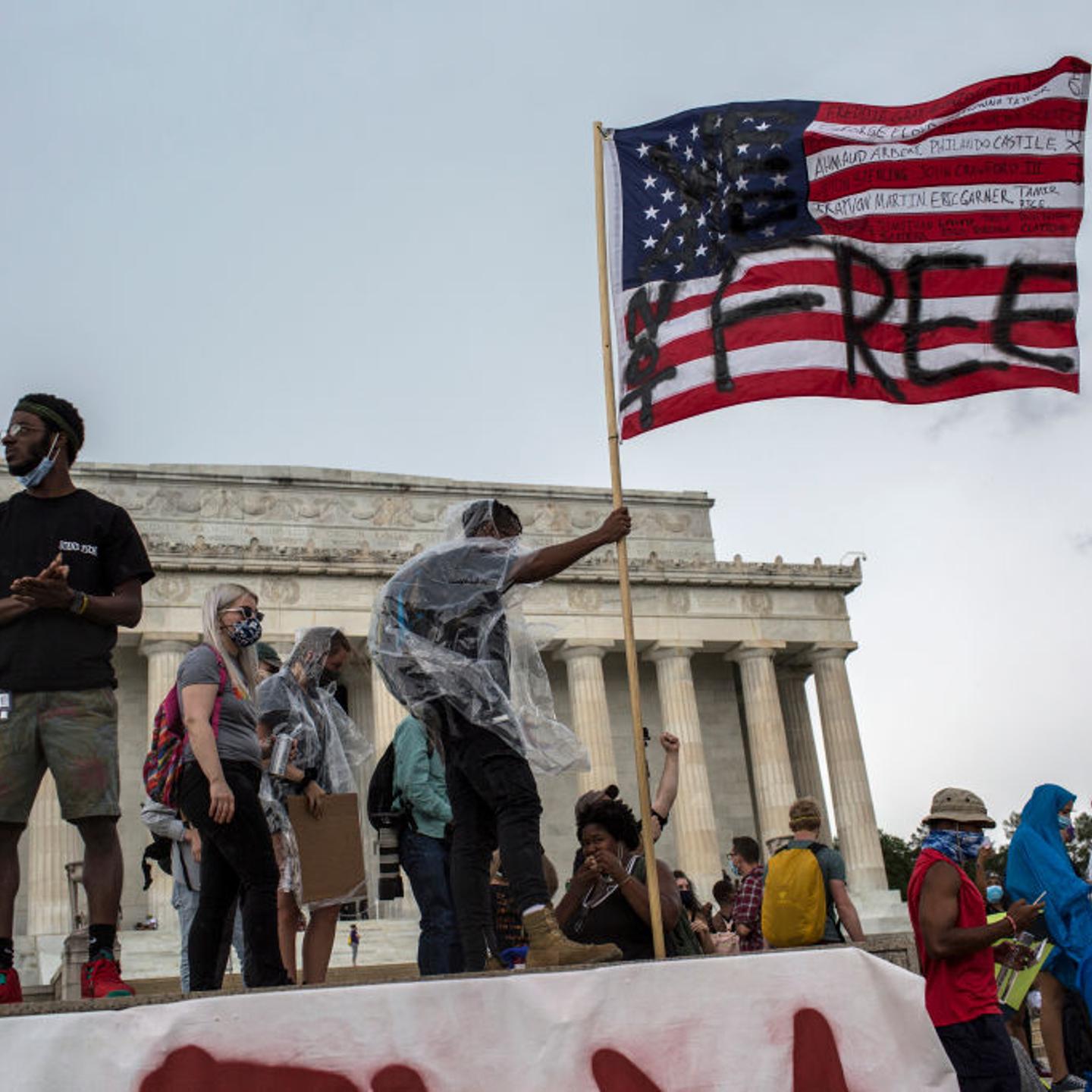 A man waves an American flag with the words "Not Free"