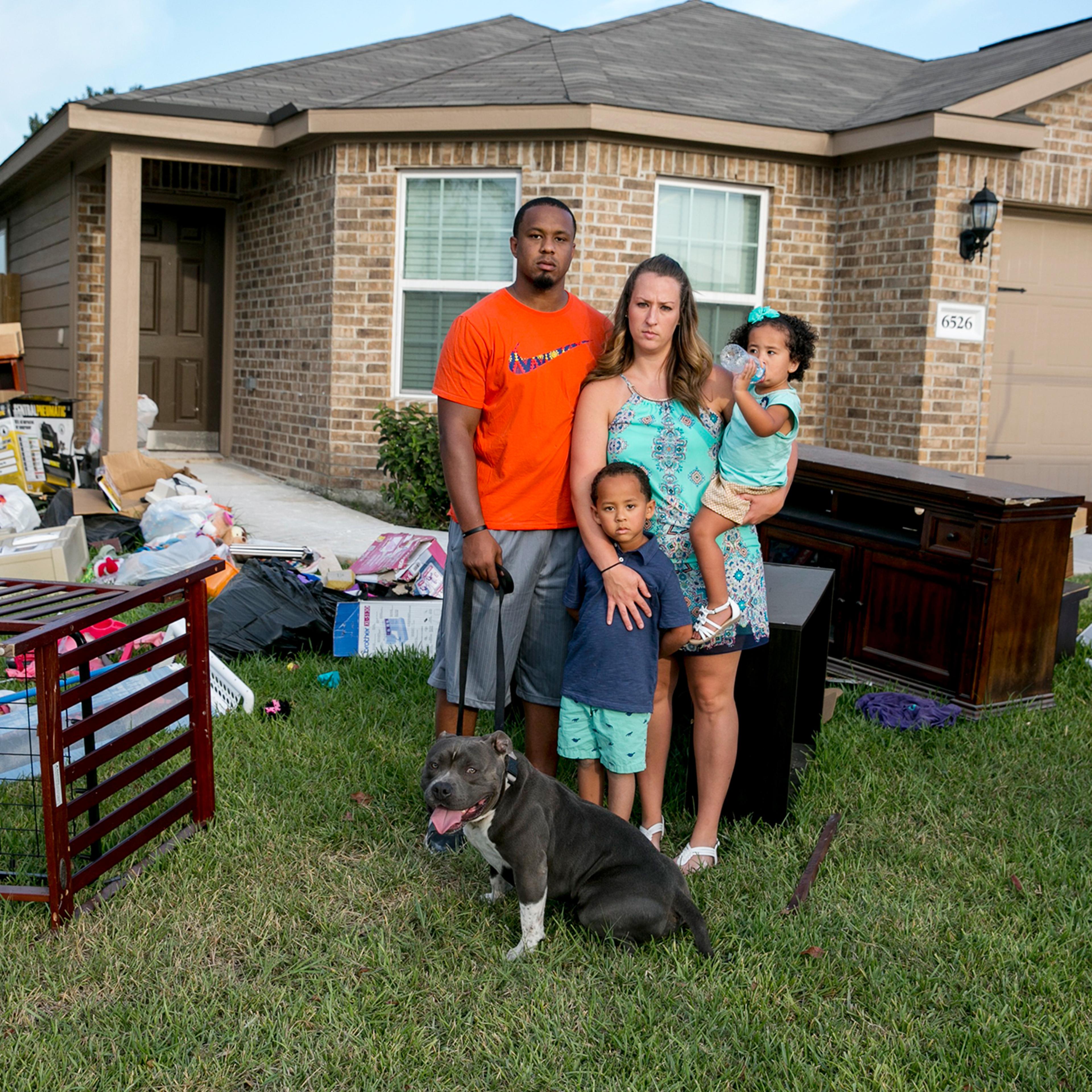 Isiah Courtney stands in the front yard of his Houston home with his wife, Danielle, son Bryson, daughter Aubree and dog Bruce