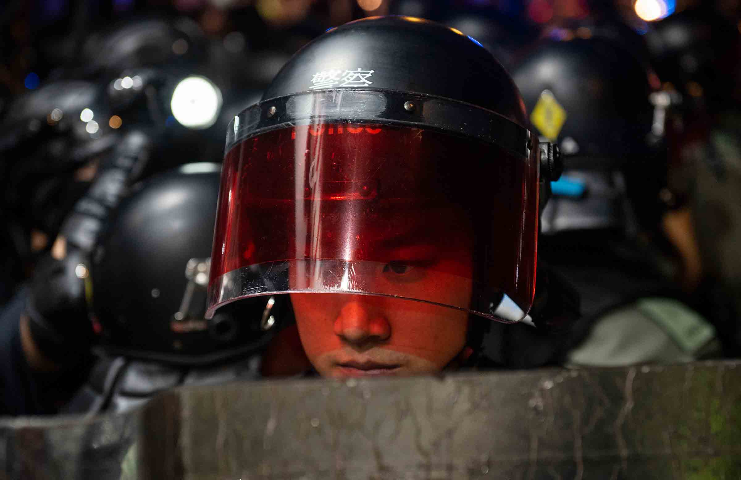 A riot-police officer watches protesters in Hong Kong on Sept. 21