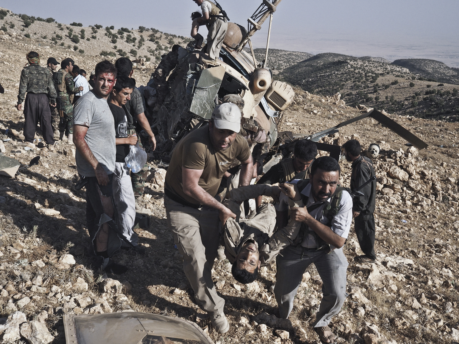 A wounded man is carried away from the crash site of an Iraqi Air Force helicopter that crashed shortly after take off during a rescue mission in the Sinjar Mountains, Iraq, Aug. 12, 2014.