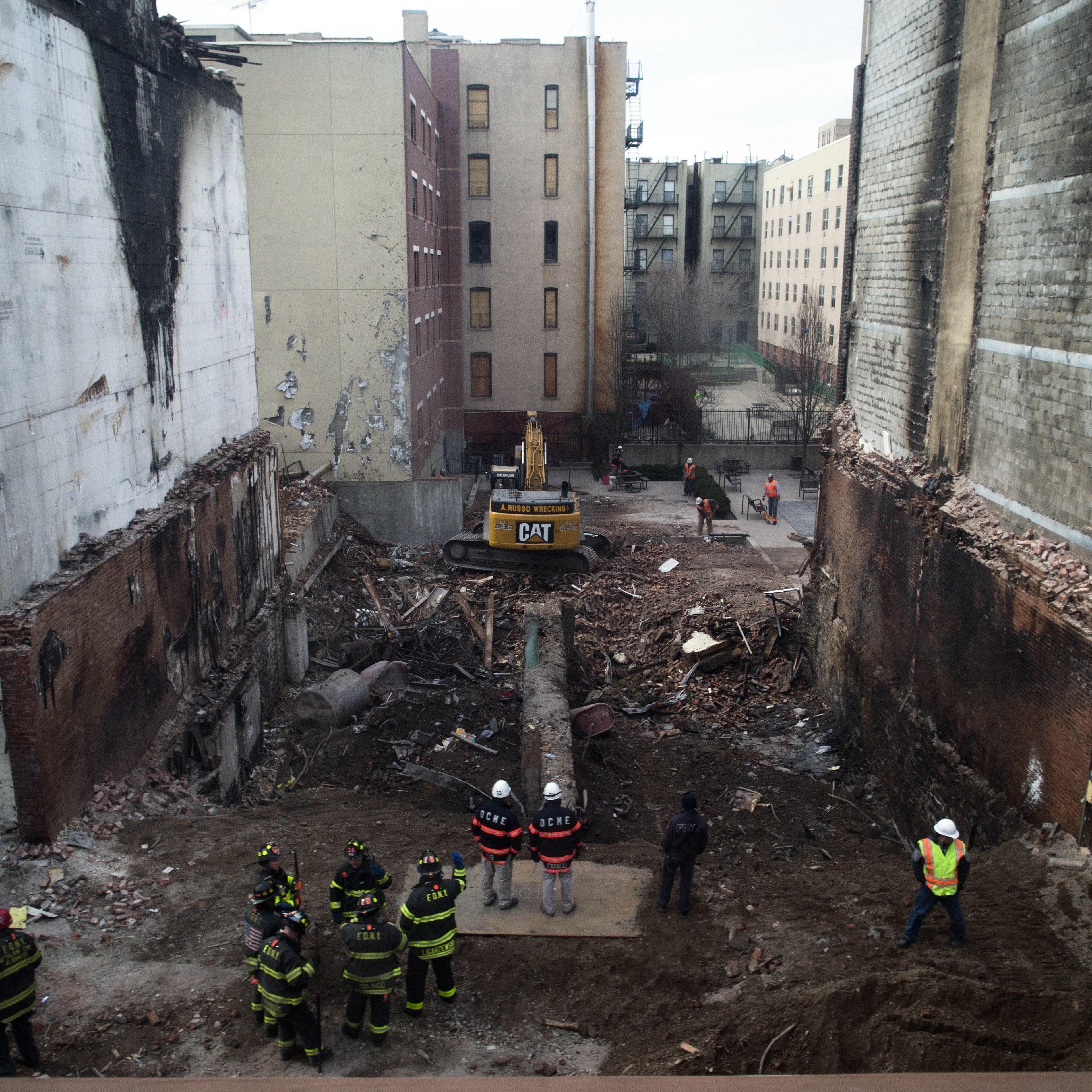 Workers stand beside the recently cleared basement of the two buildings leveled by an explosion on Wednesday in the East Harlem neighborhood of New York