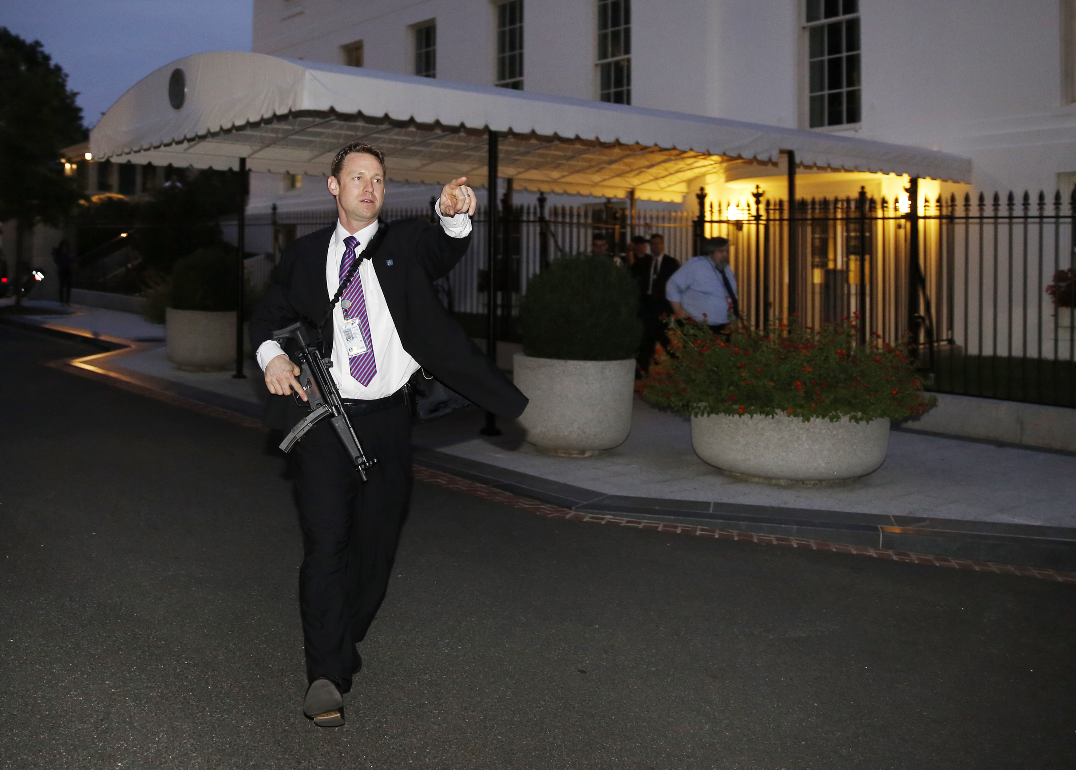A U.S. Secret Service agent with an automatic rifle hurries people to evacuate the White House complex over a security alert moments after President Barack Obama and his family left for the presidential retreat, Camp David, in Maryland