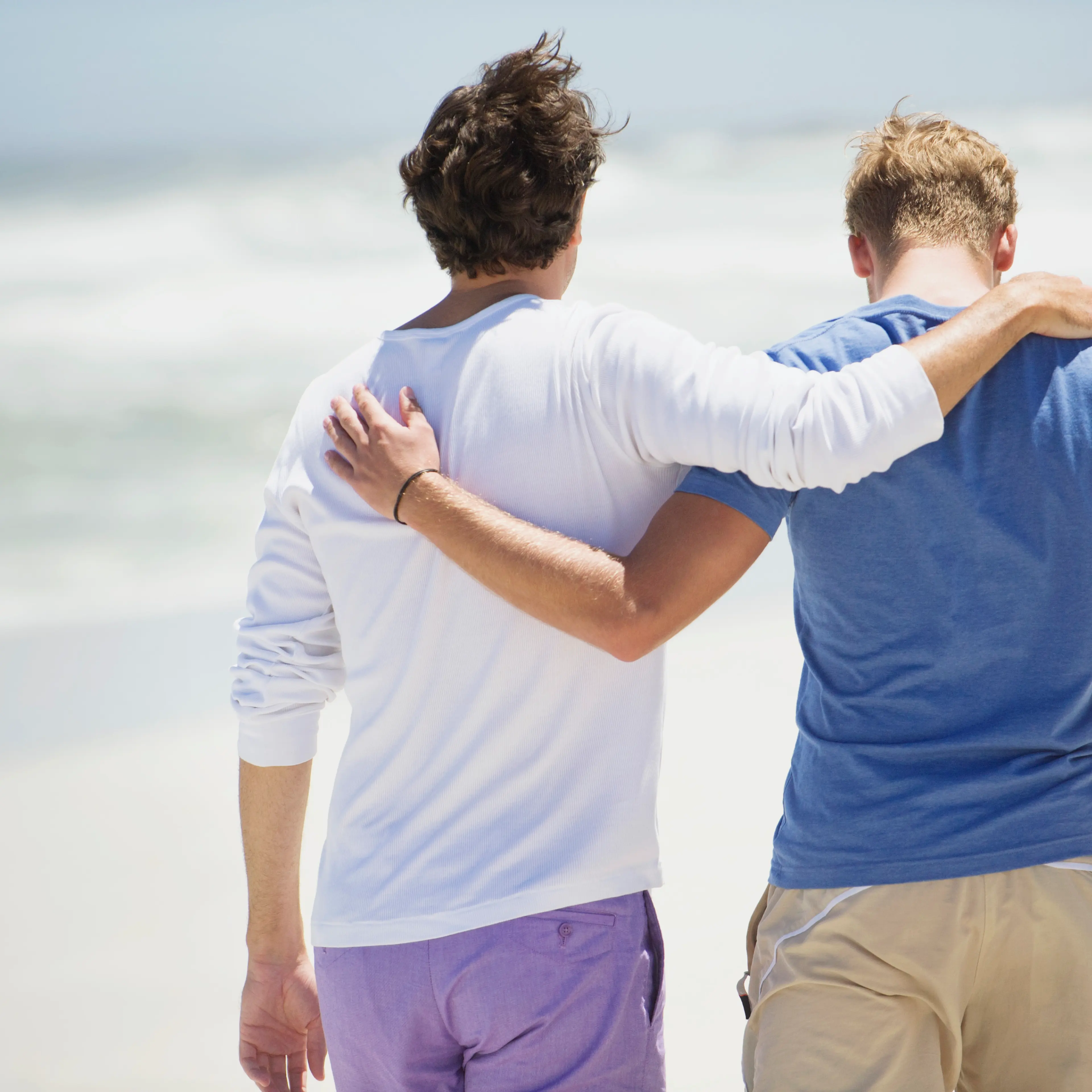 Rear view of two men walking with their arms around each other