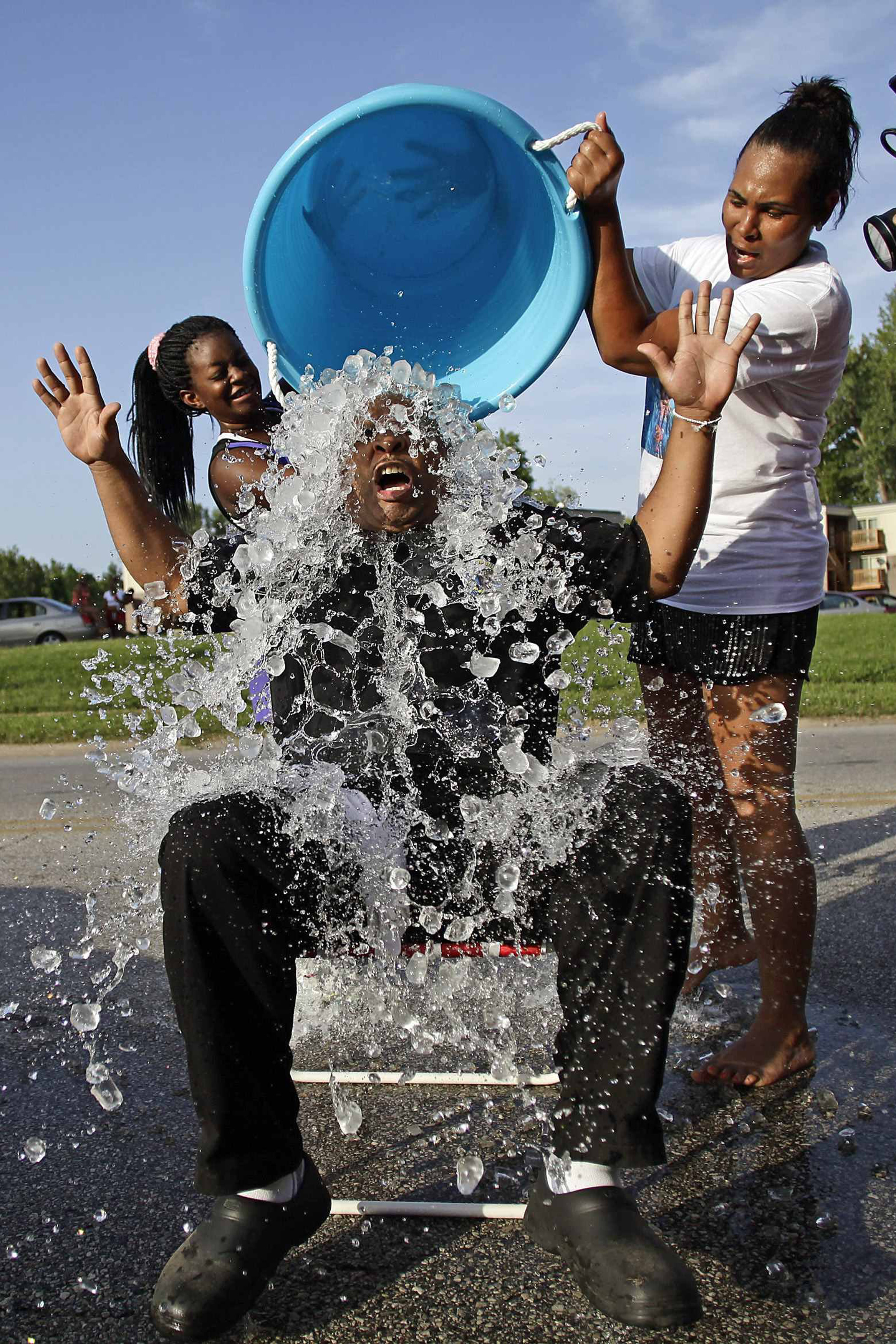 Supporters of Michael Brown, Kalisha Gilmore (L) and Recorida Kennedy (R), pour ice water on Kevin Ephron as he takes the ice bucket challenge in remembrance of Brown along Canfield Drive, where he was fatally shot by a police officer in Ferguson, Missou