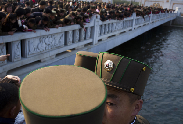 North Korean soldiers and civilians stand on a foot bridge to look at goldfish in a moat as they tour the grounds of Kumsusan Palace of the Sun, the mausoleum where the bodies of the late leaders Kim Il Sung and Kim Jong Il lie embalmed, in Pyongyang on 