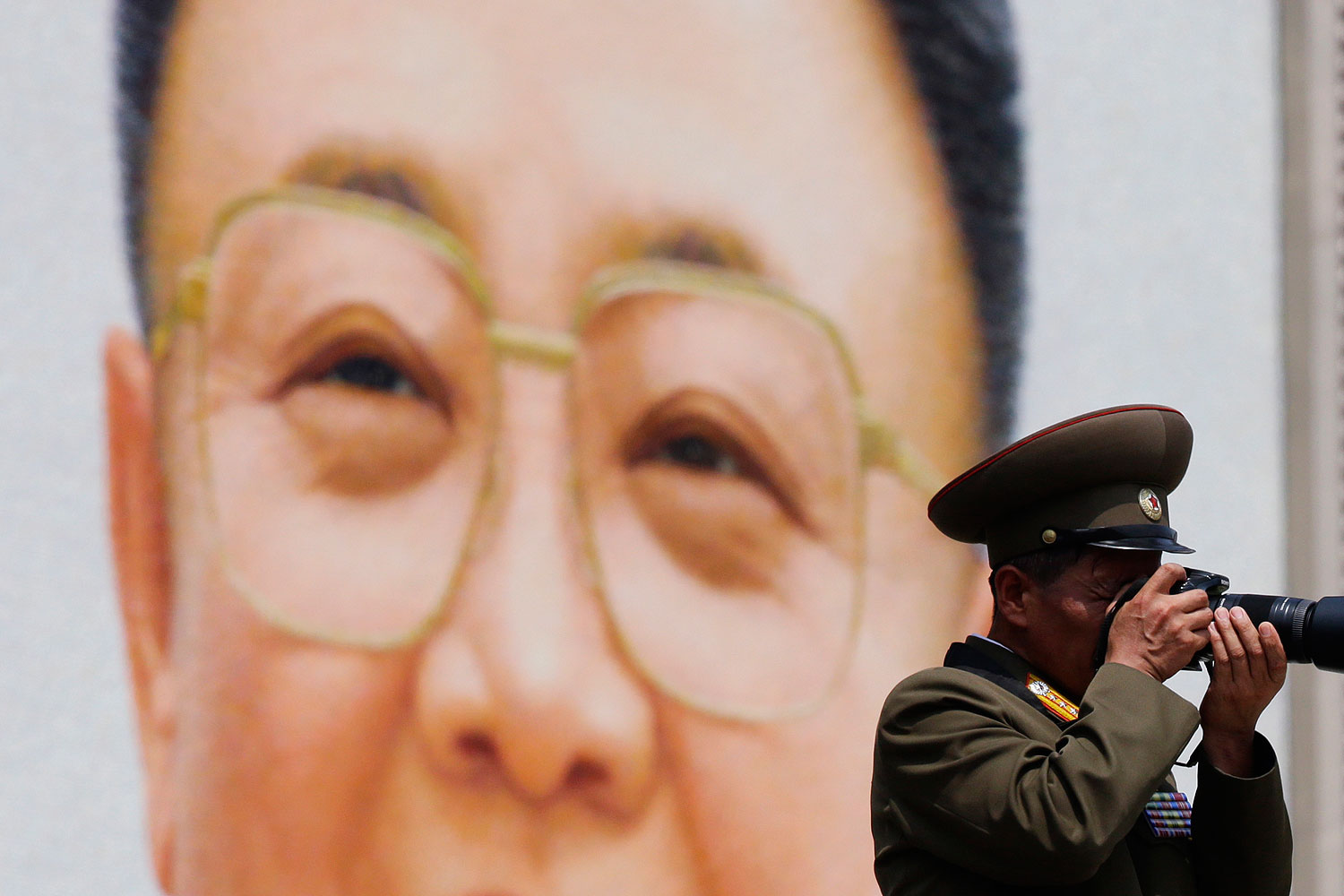 A military officer takes a photograph in front of a giant portrait of late North Korean leader Kim Jong-il during a parade to mark the 60th anniversary of the signing of a truce in the 1950-1953 Korean War at Kim Il-sung Square, in Pyongyang July 27, 2013