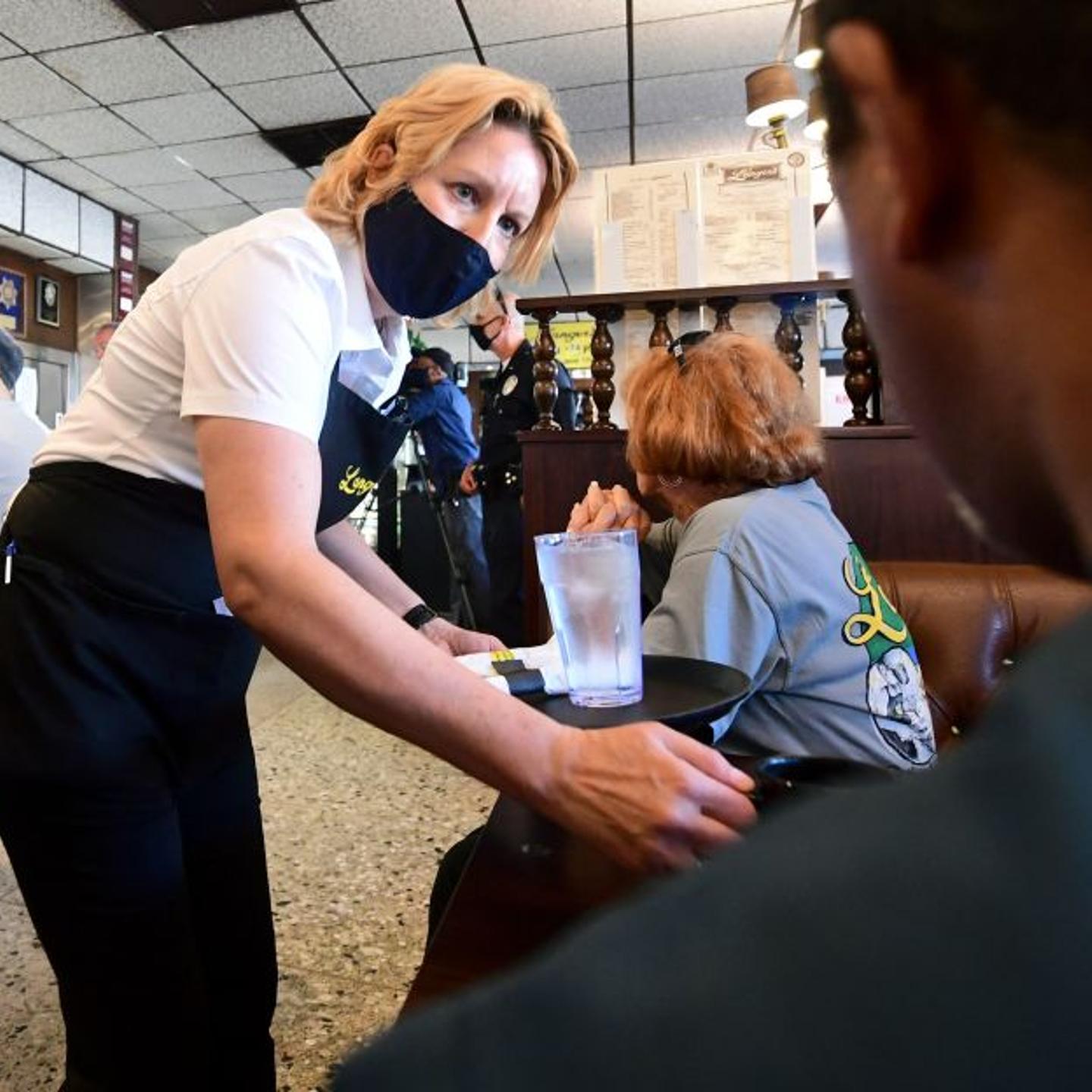 a waitress wears a face mask while serving at Langer's Delicatessen-Restaurant in Los Angeles, California