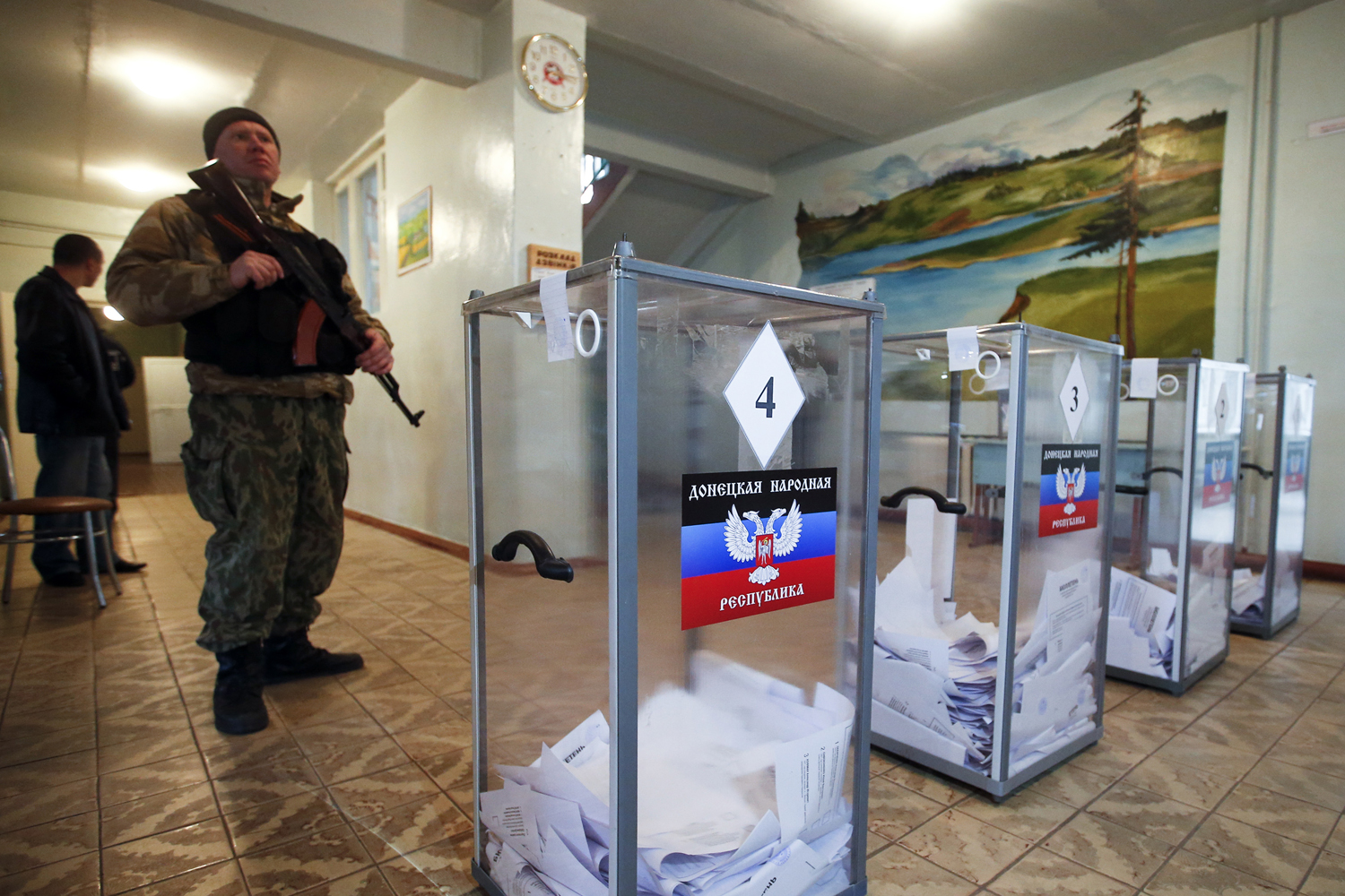 A pro-Russian separatist stands guard during the self-proclaimed Donetsk People's Republic leadership and local parliamentary elections at a polling station in the settlement of Telmanovo