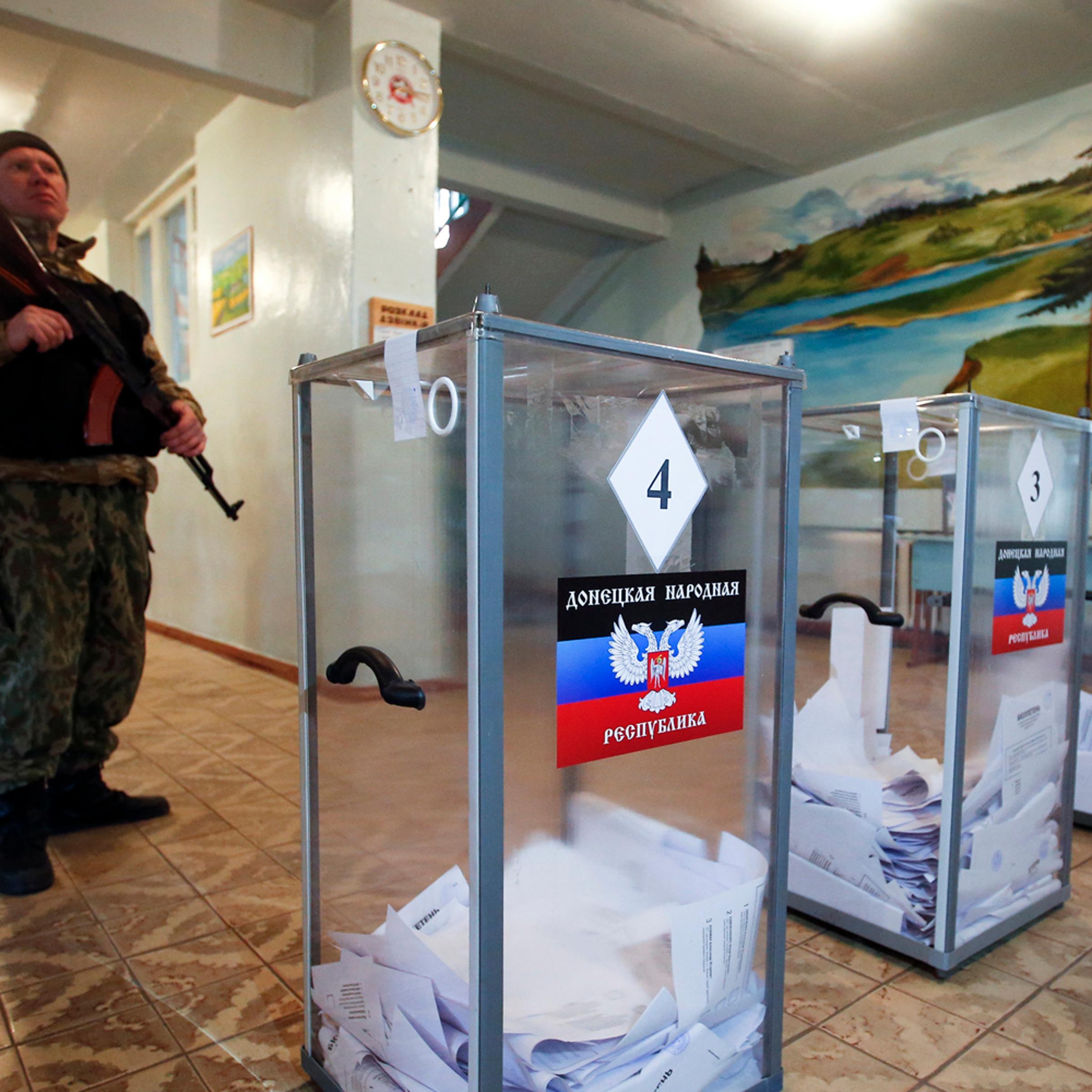 A pro-Russian separatist stands guard during the self-proclaimed Donetsk People's Republic leadership and local parliamentary elections at a polling station in the settlement of Telmanovo