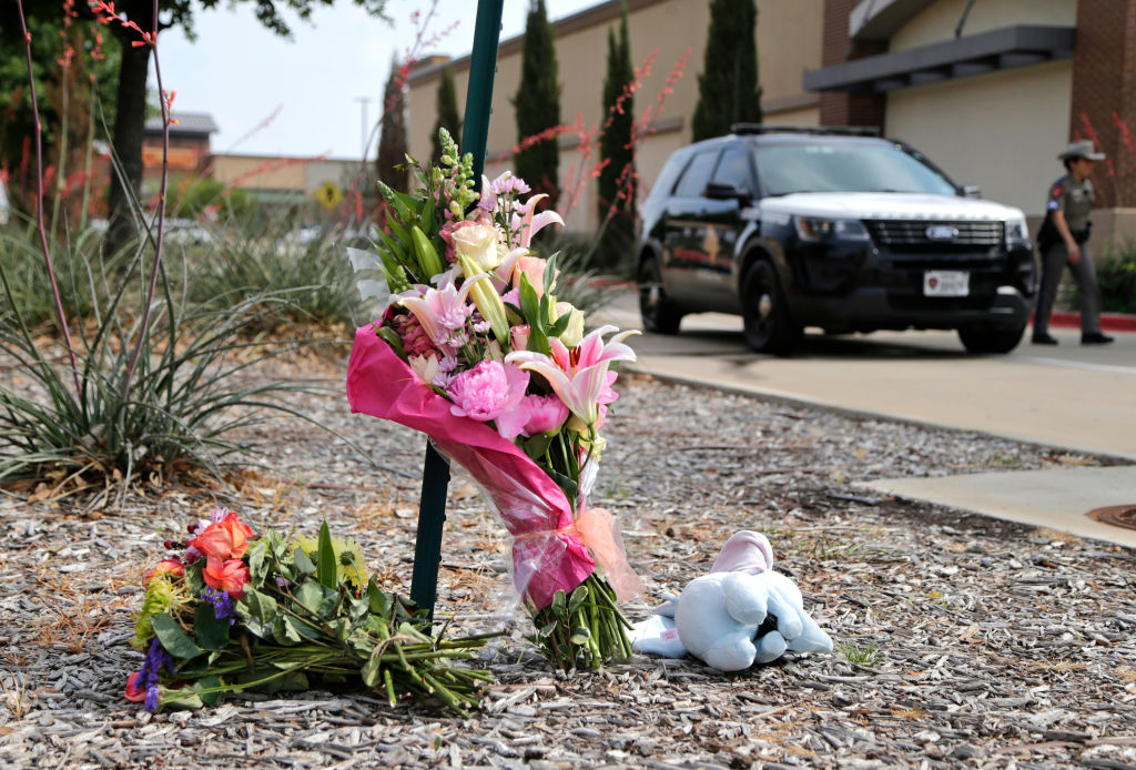 Flowers and a stuffed animal are left at the scene the day after a shooting at Allen Premium Outlets in Allen, Texas