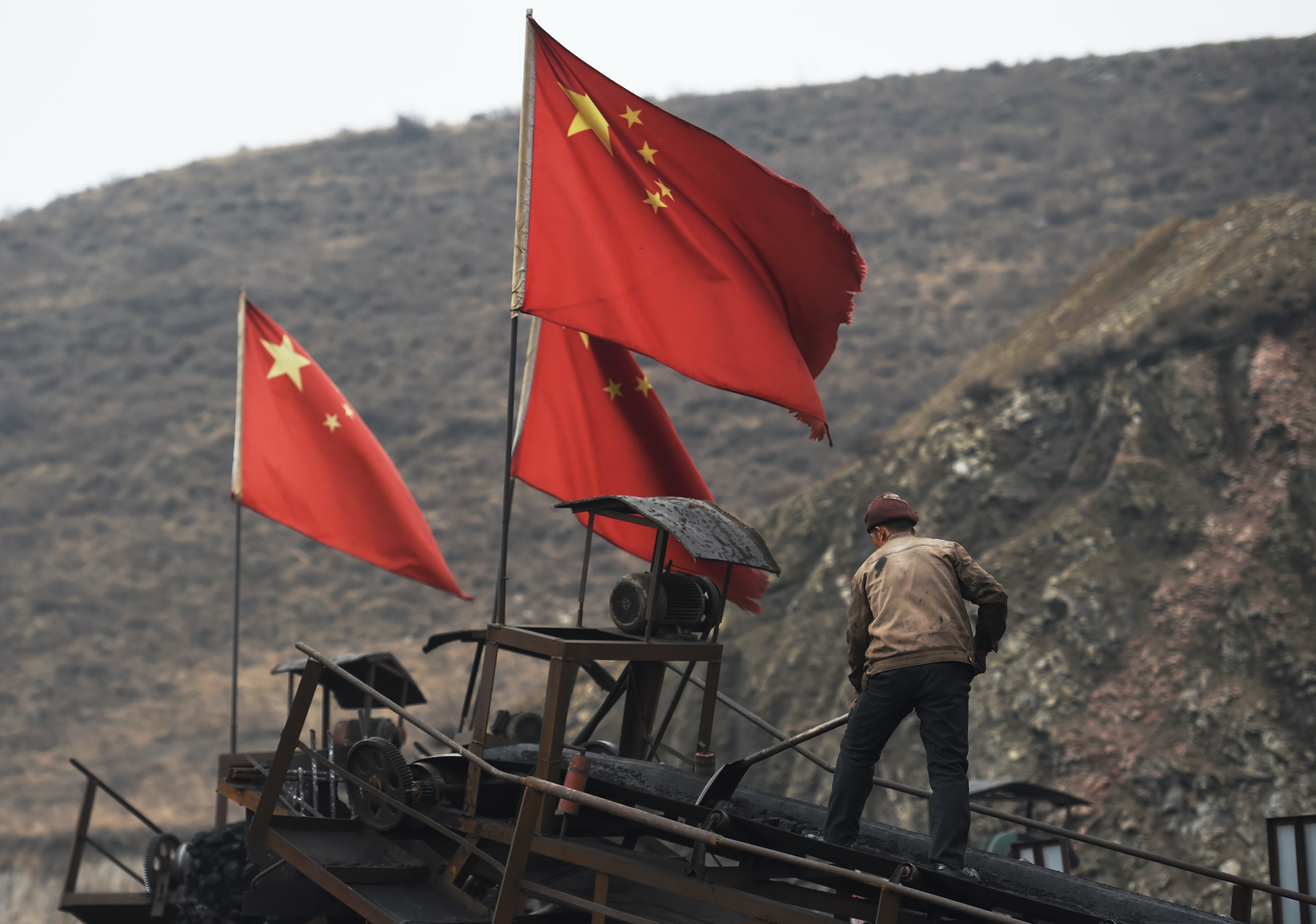 A worker clears a conveyer belt used to transport coal, near a coal mine at Datong, in China's northern Shanxi province on Nov. 20, 2015.