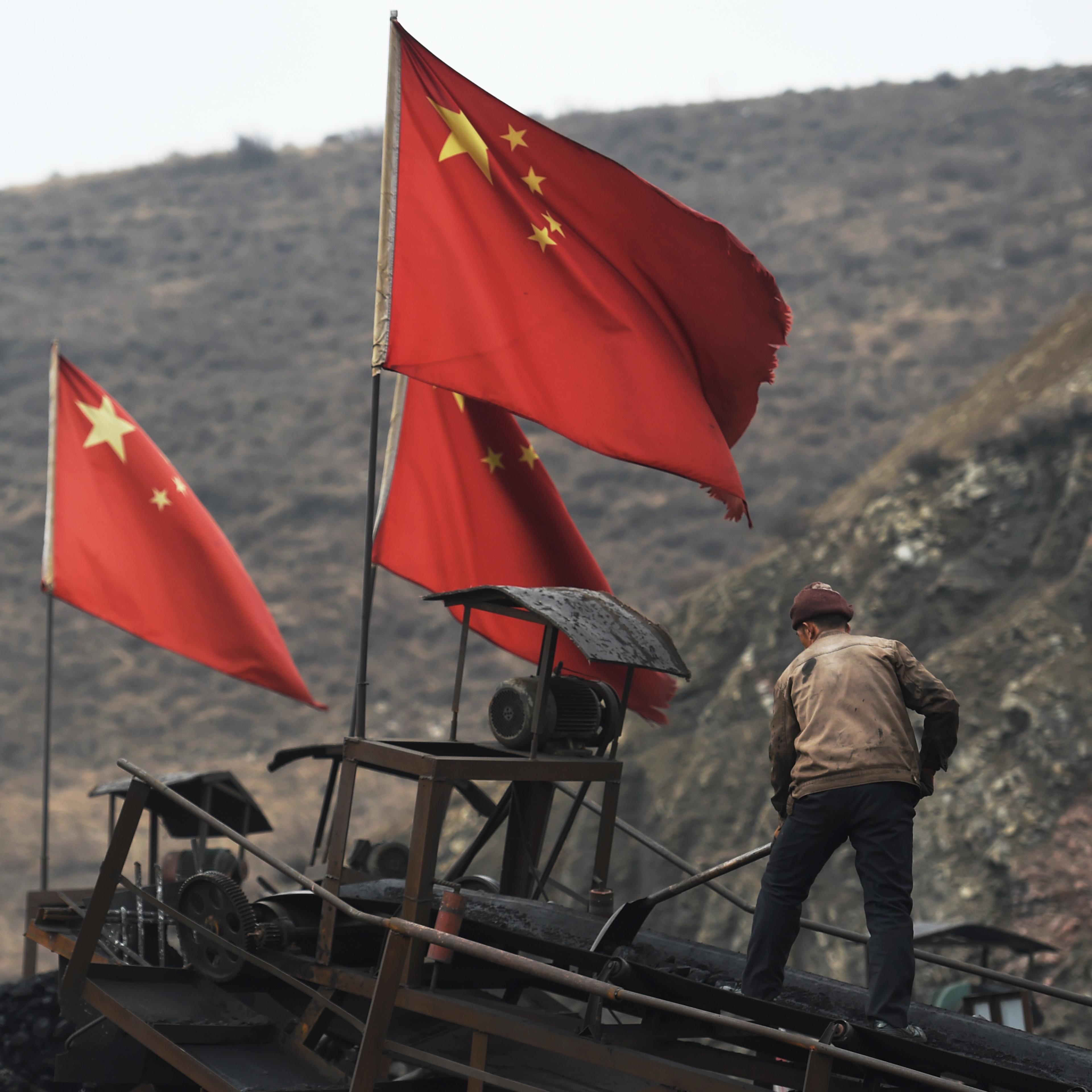 A worker clears a conveyer belt used to transport coal, near a coal mine at Datong, in China's northern Shanxi province on Nov. 20, 2015.